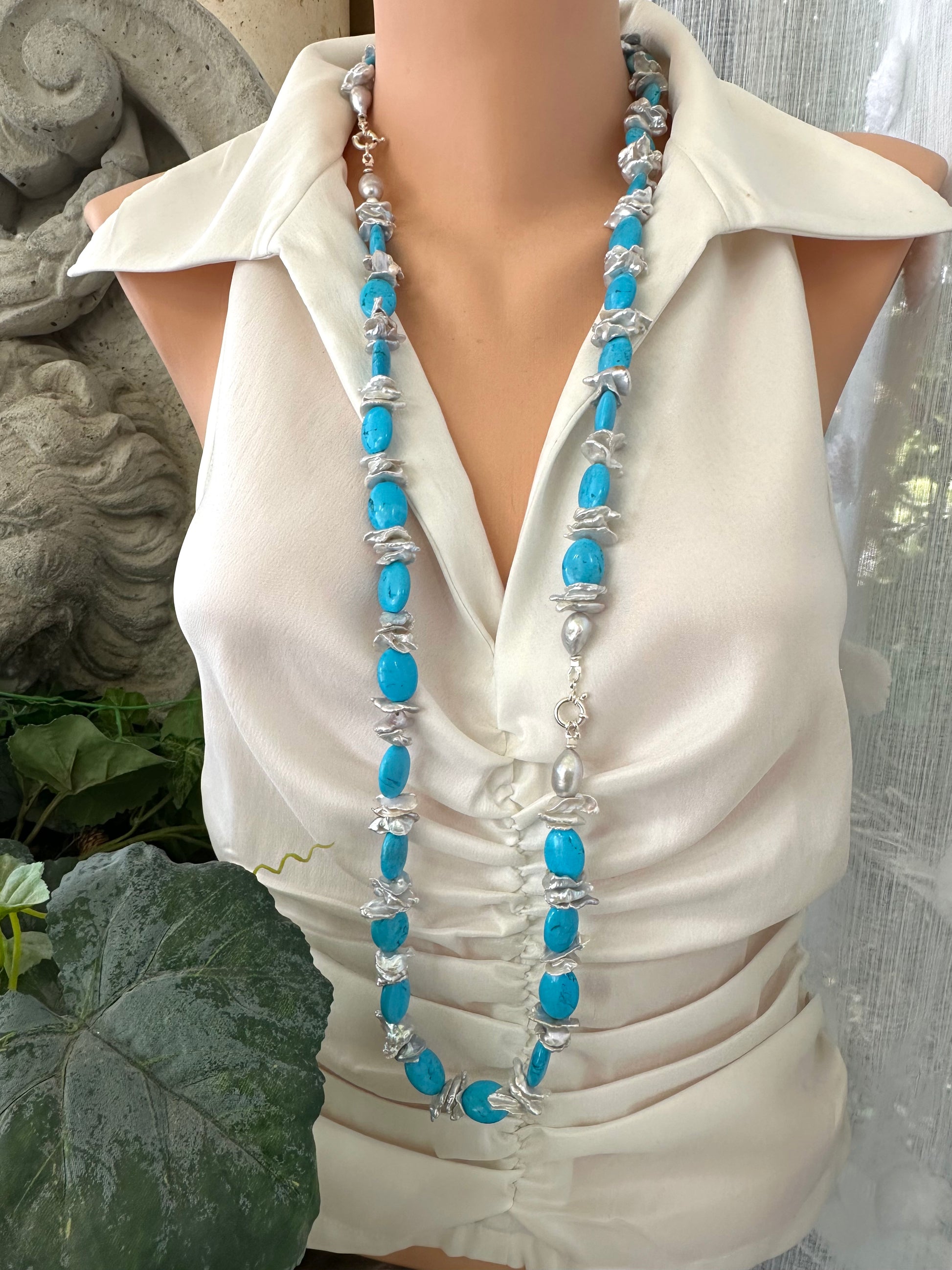 Long chunky turquoise and silver grey keshi pearl necklace worn on mannequin, draping to mid-torso