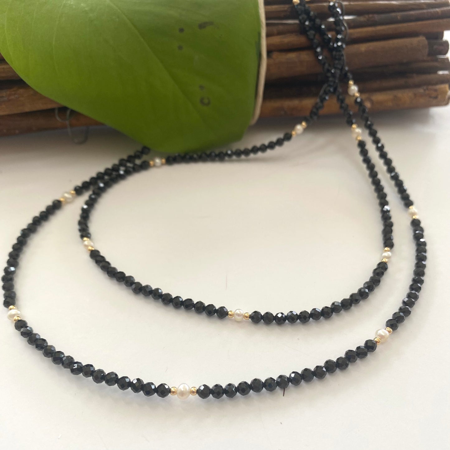 Double strand black spinel pearl choker necklace on white fabric