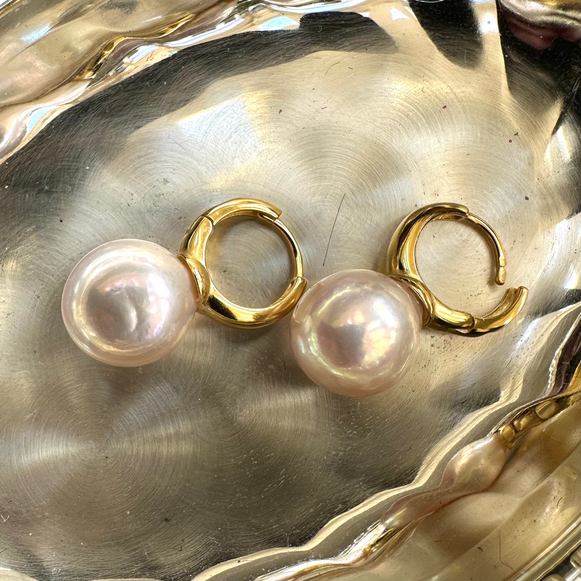Golden pink pearl hoop earrings with luminous Edison pearls placed on shell, emphasizing handmade Canadian craftsmanship.