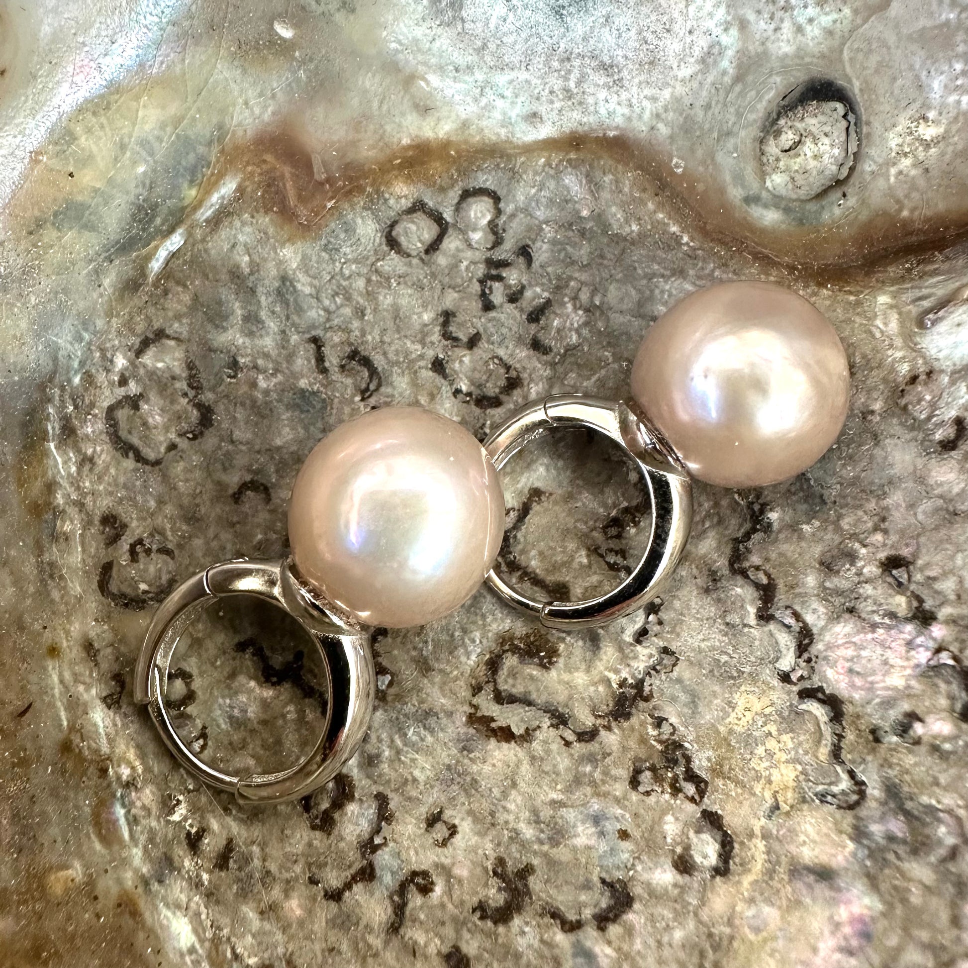 Light pink pearl hoop earrings featuring 13 mm Edison pearls and silver accents, showcasing elegance and modern luxury.