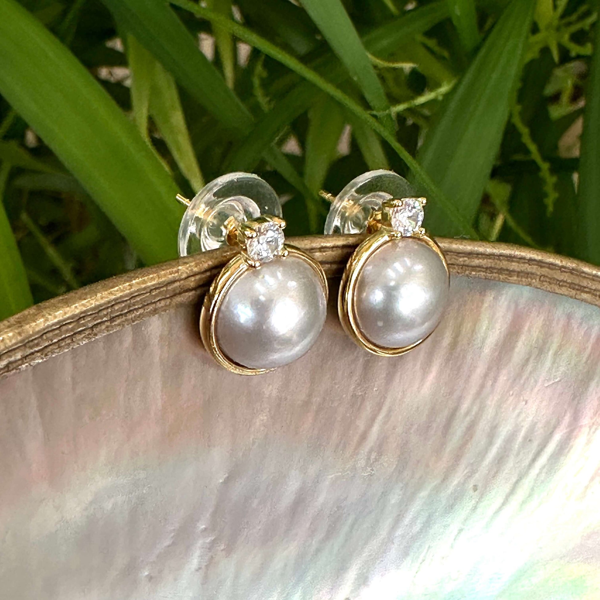 Silver grey pearl stud earrings with CZ – Gold Vermeil displayed on a natural shell background.