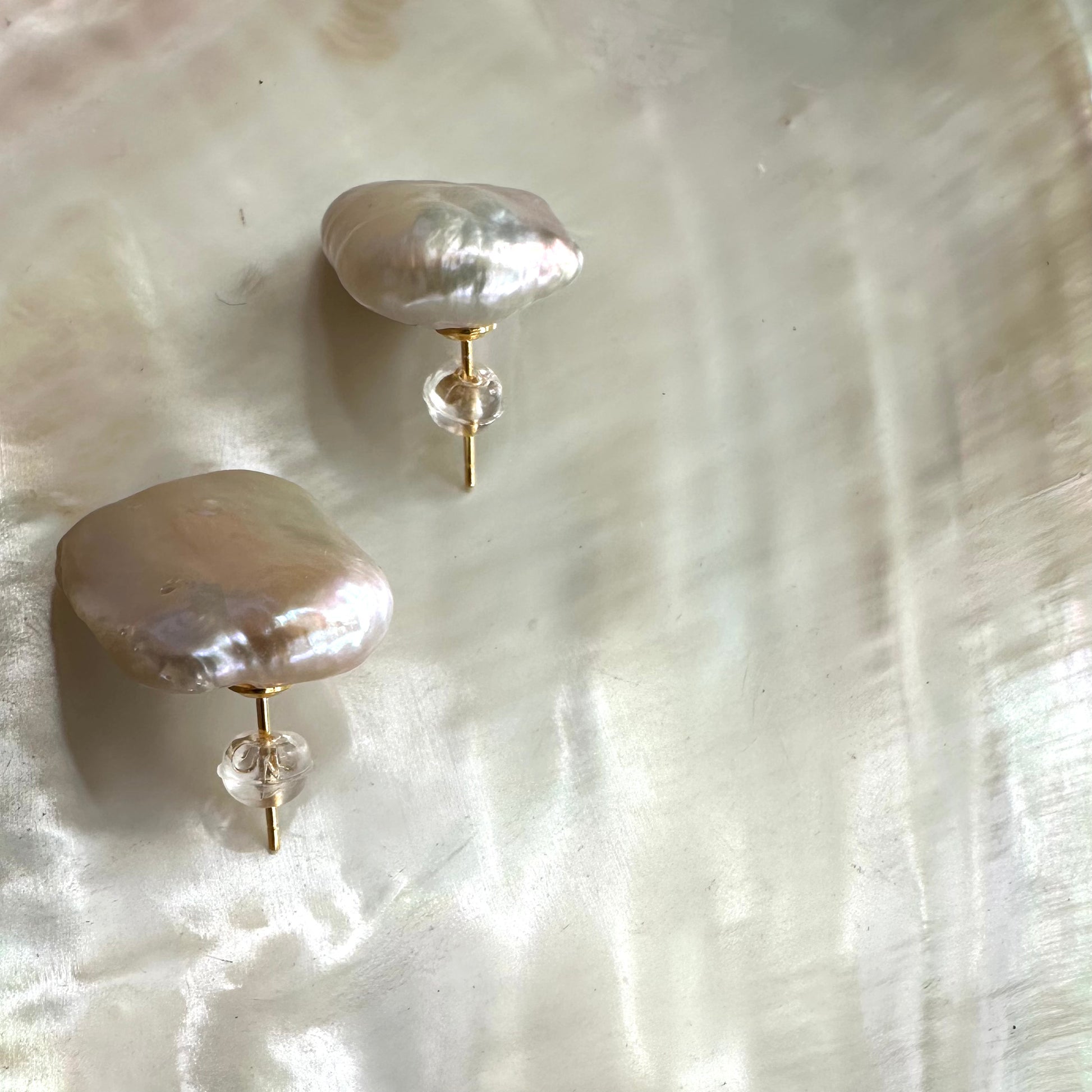 Baroque pearl stud earrings showcasing unique, organic shapes on a pearlescent background.