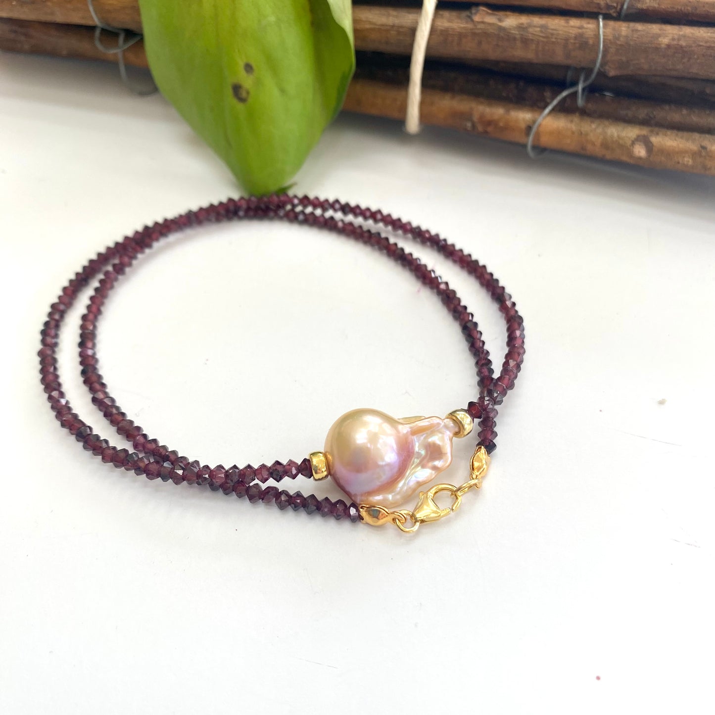 Red garnet baroque pearl necklace featuring a golden pink pearl pendant in an elegant design.