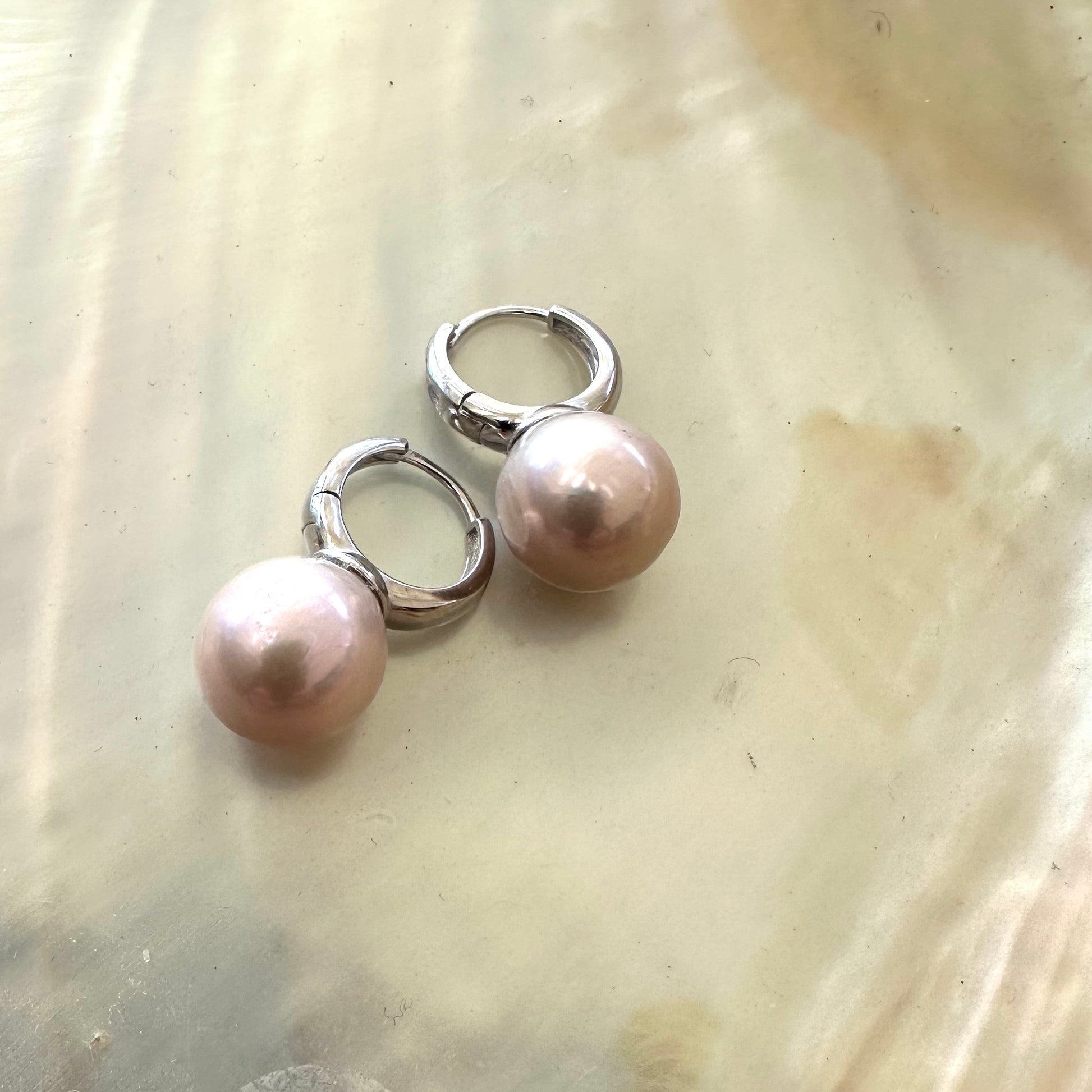 Light pink pearl hoop earrings – Edison Pearls, Silver on a pearlescent background, showcasing elegance and luxury.