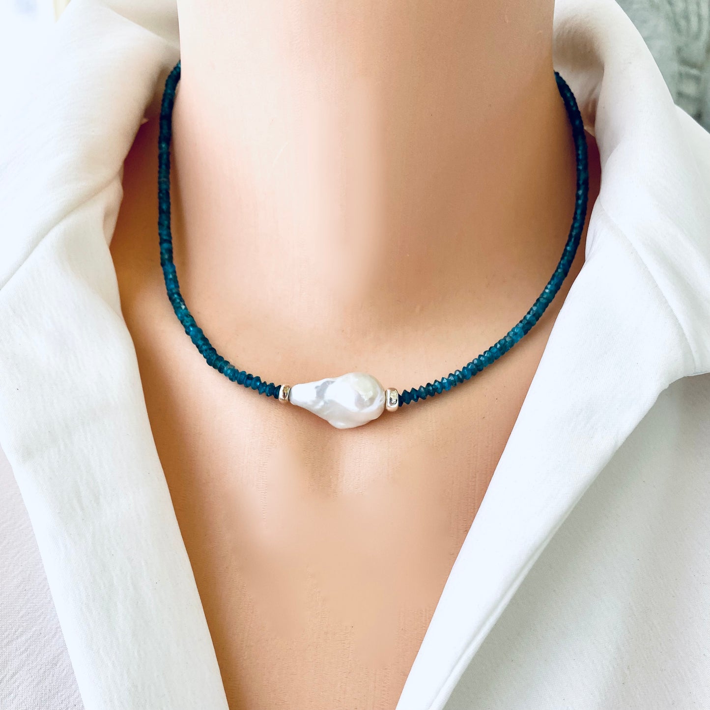 Dark blue apatite baroque pearl necklace featuring blue apatite beads and a white Baroque pearl centerpiece.