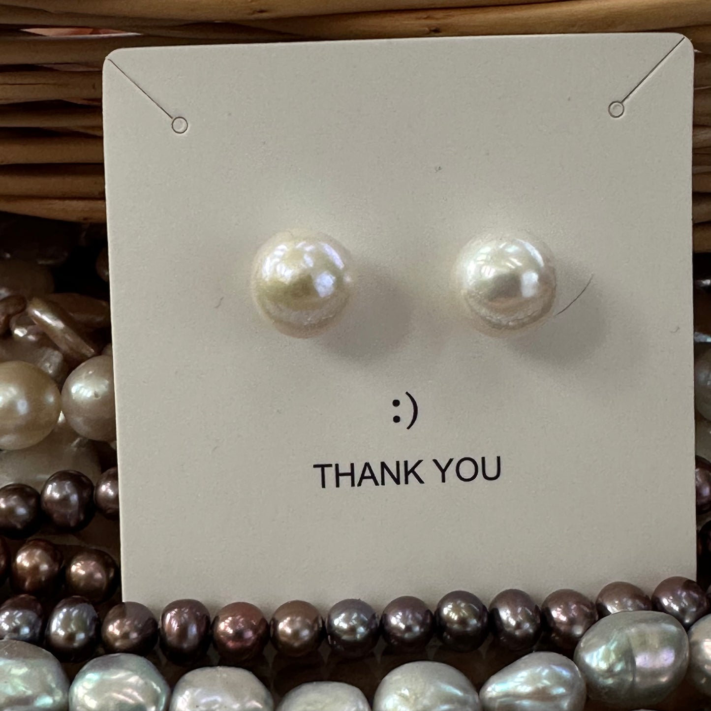White edison pearl stud earrings attached to white jewelry package, showing gold vermeil setting and luxurious presentation.