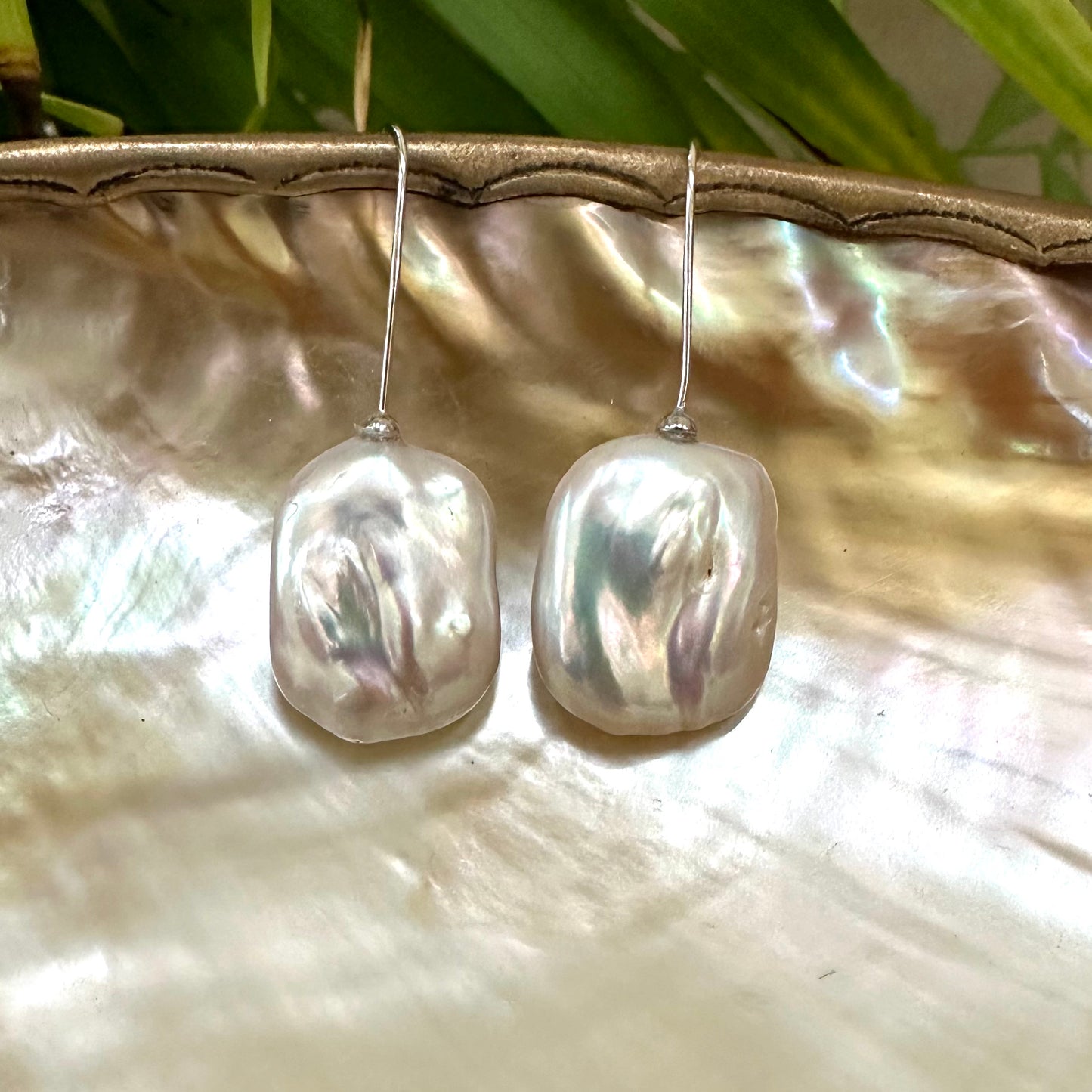 White freshwater pearl drop earrings rhodium-plated silver detailed view against leaf backdrop, elegant handmade jewelry from Canada.