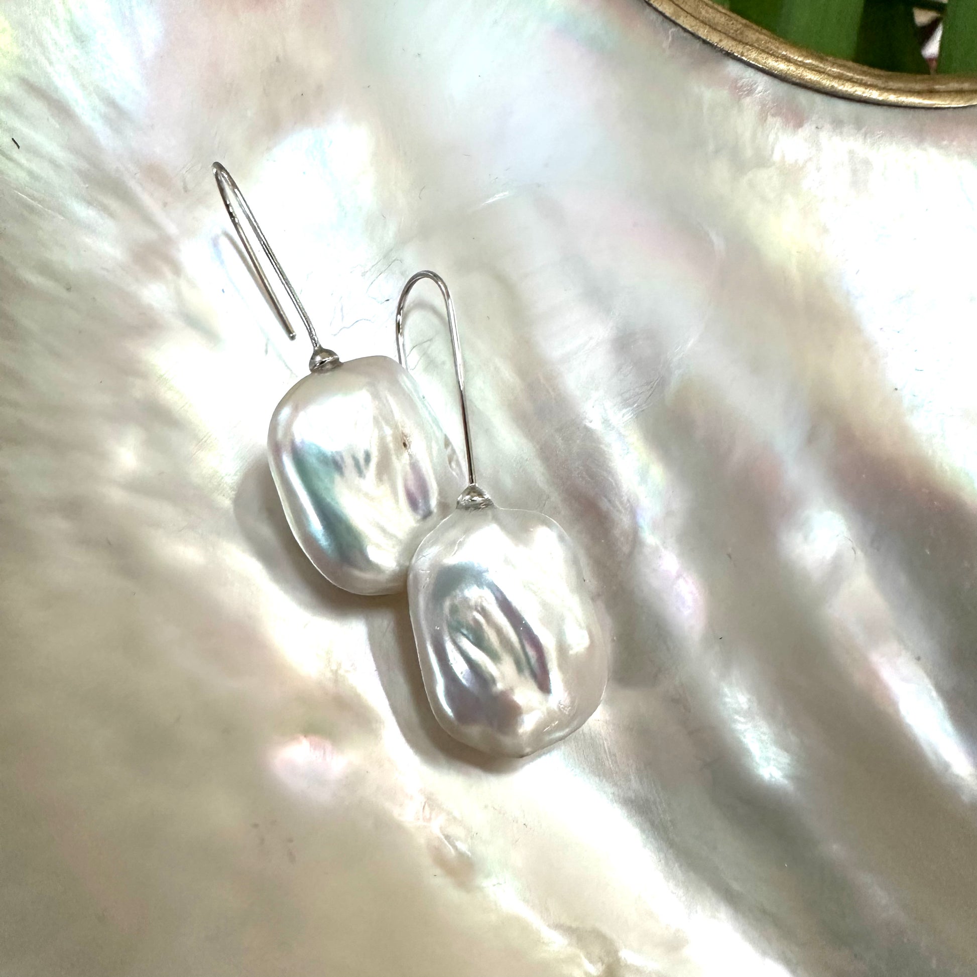 White freshwater pearl drop earrings rhodium-plated silver close-up on white pearl shell, rectangular design handmade in Canada.