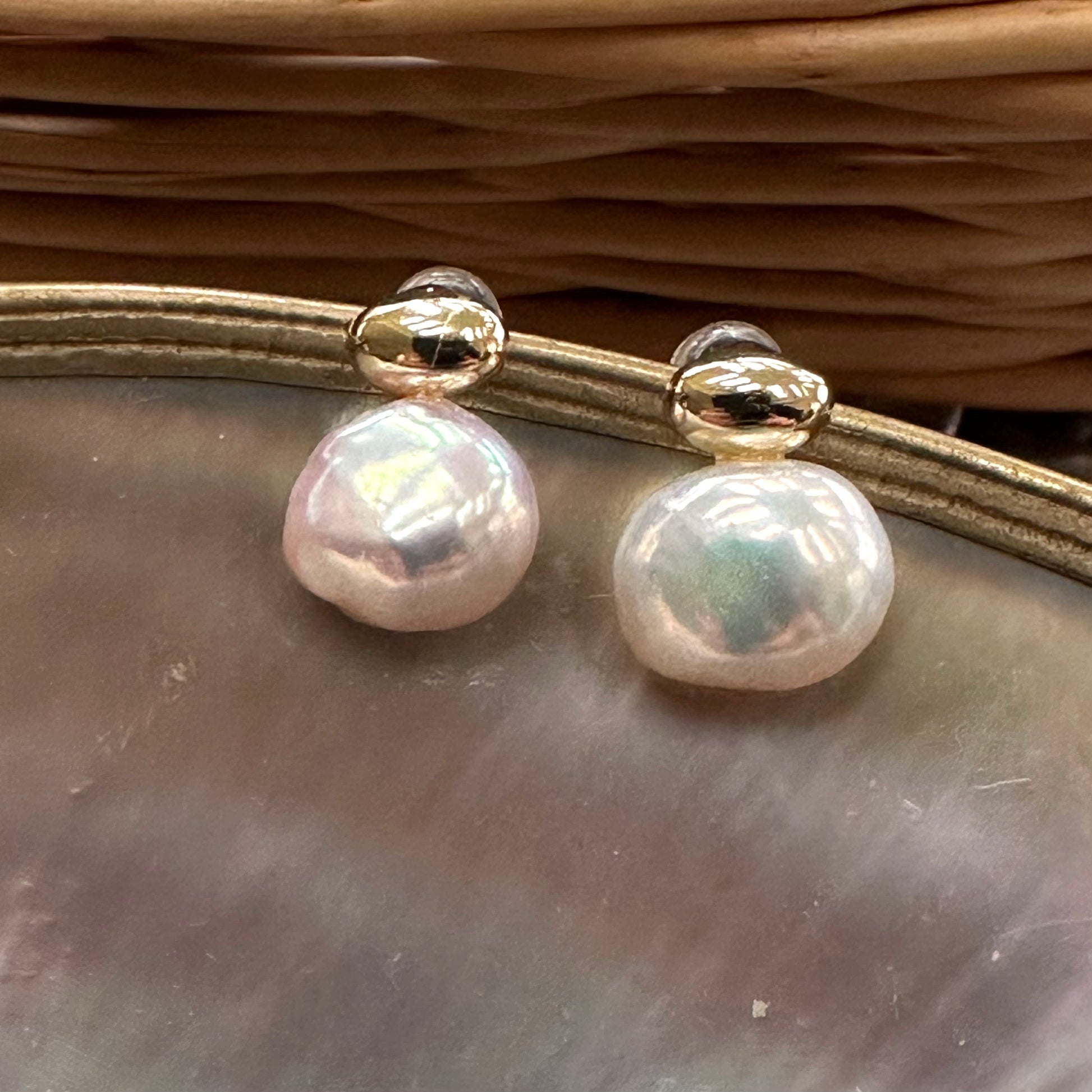 Handmade nugget pearl earrings with natural luster on shell background