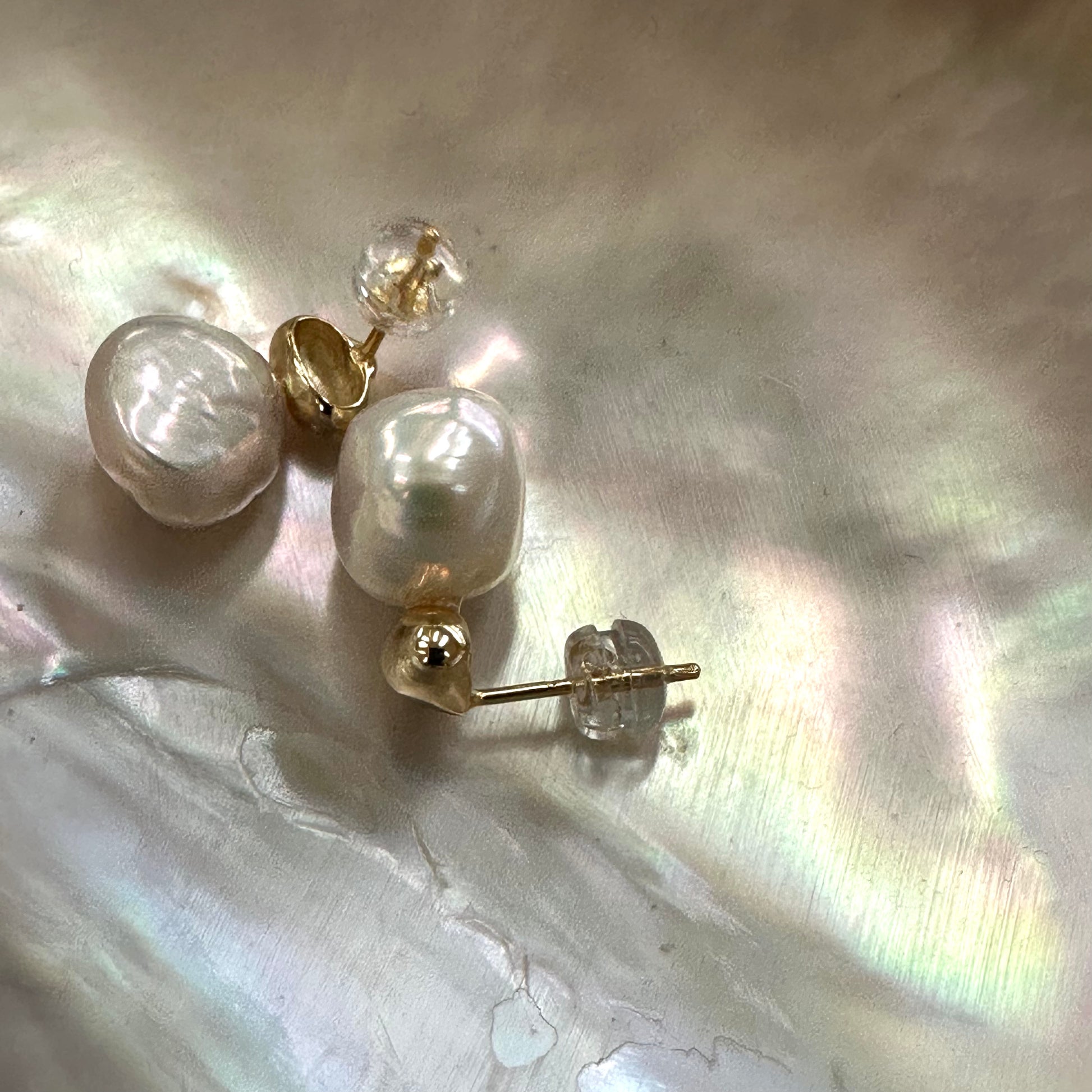 Gold vermeil nugget pearl stud earrings with separated studs on pearl shell backdrop