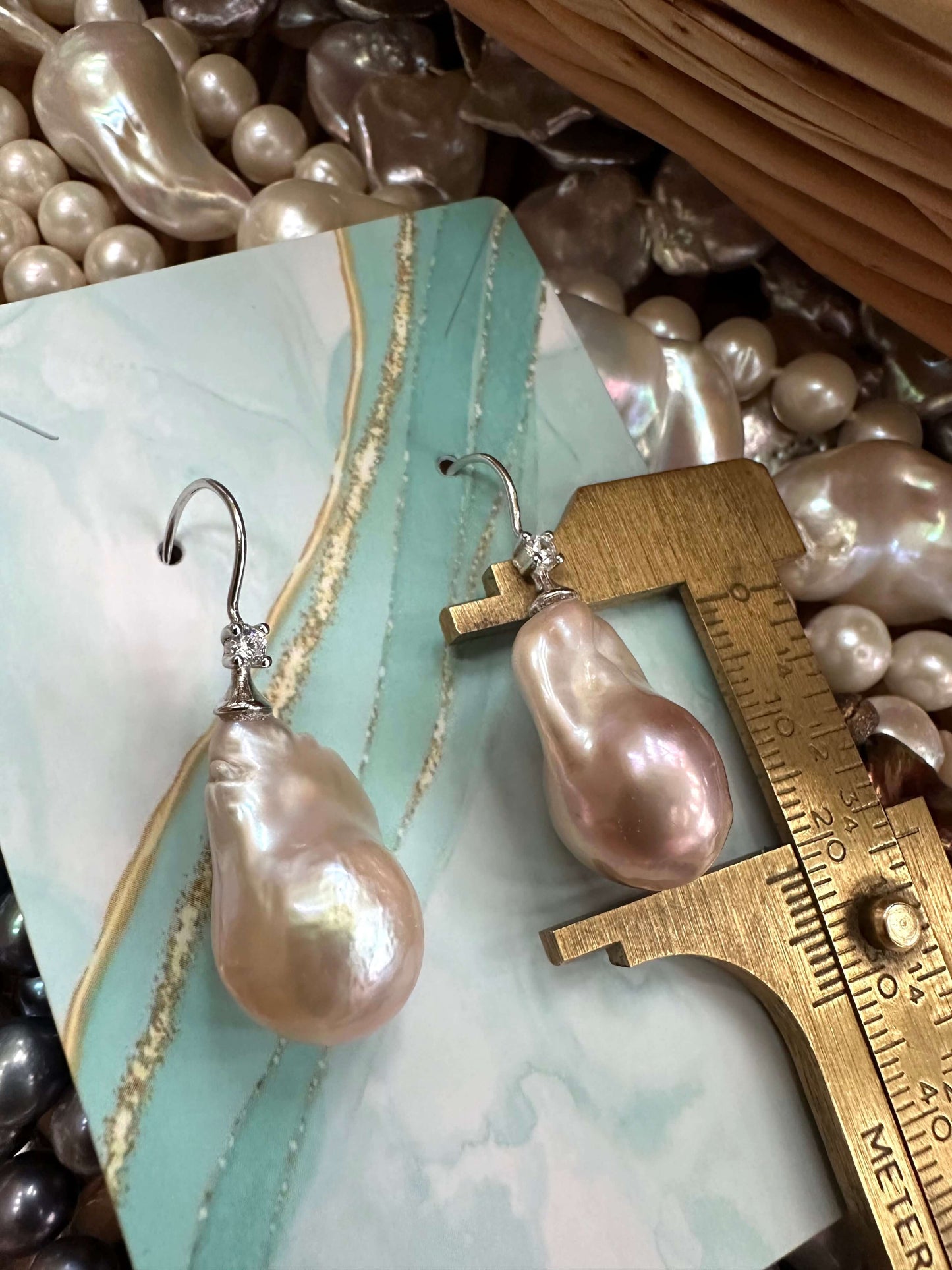 Lavender Baroque Pearl Earrings – single pearl measured against ruler on turquoise background