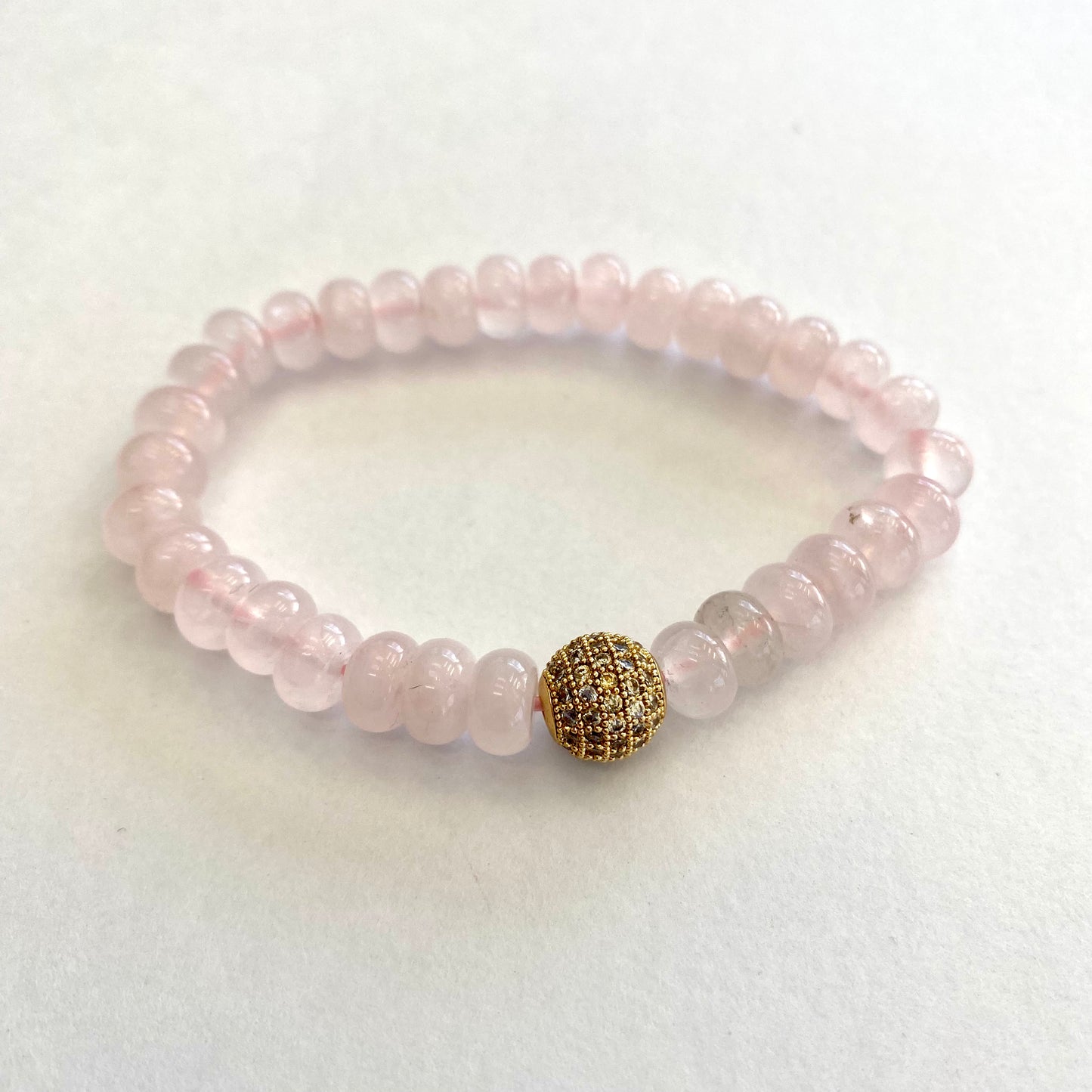 Rose quartz stretch bracelet with gold accent beads for a stylish and elegant accessory.