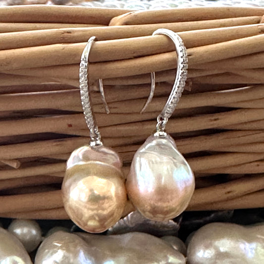 Golden pink baroque pearl dangle earrings resting on wicker basket, sterling silver CZ pavé design handmade in Canada.