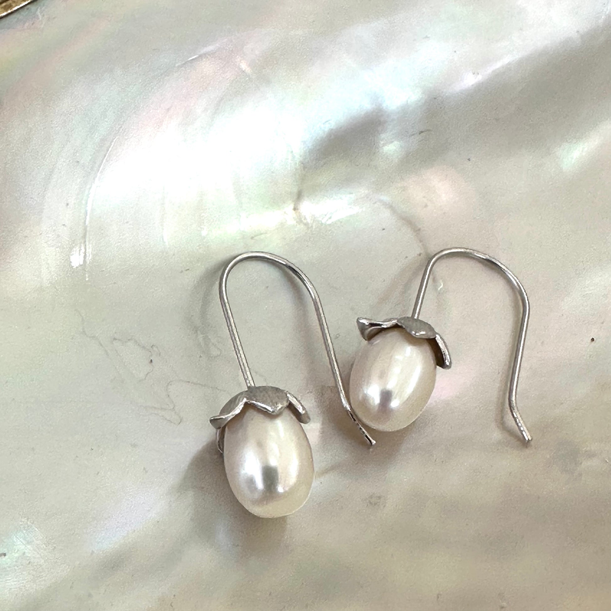 Rice Pearl Earrings – silver version close-up on white pearl shell background