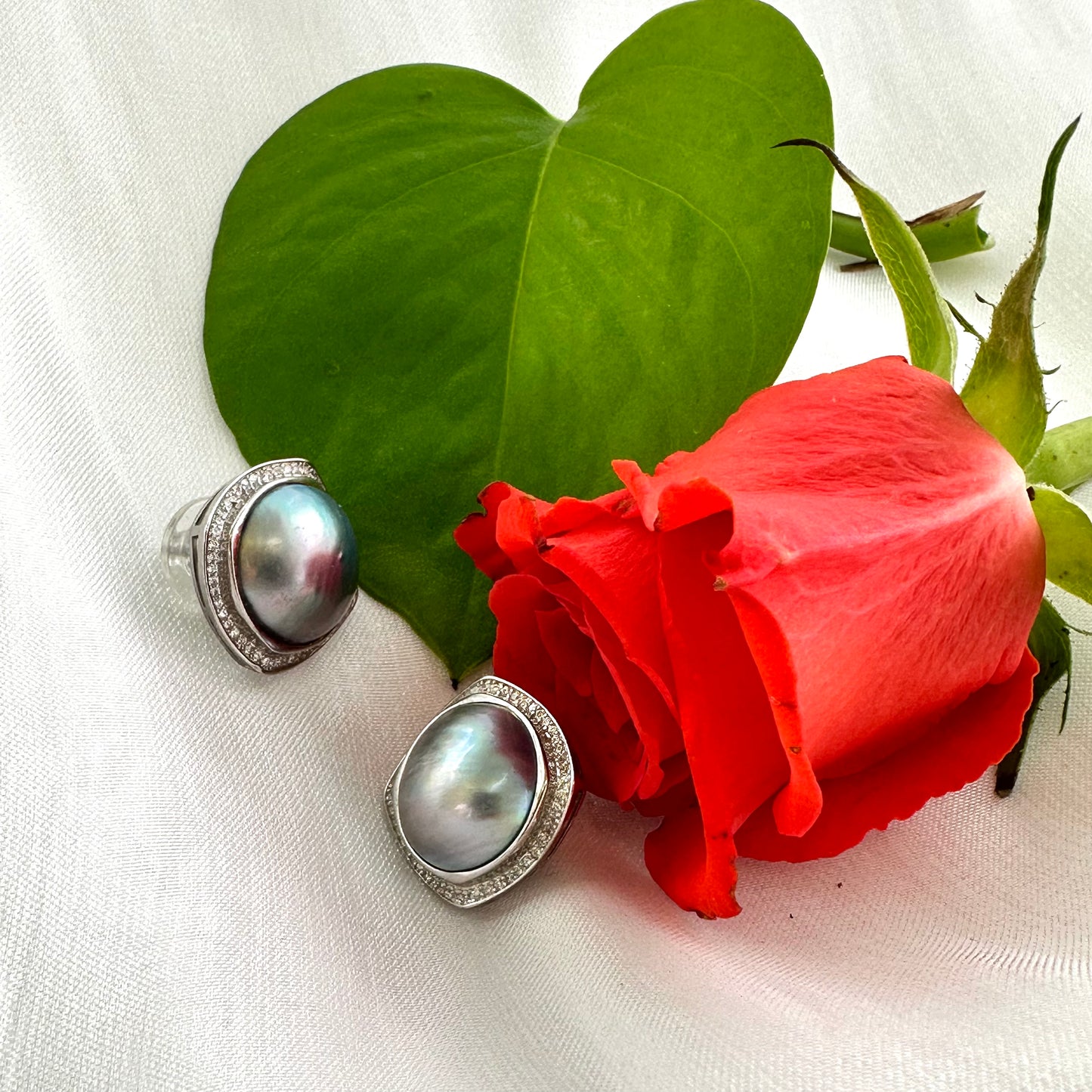 Mabe Pearl Earrings – displayed with red rose and white cloth backdrop