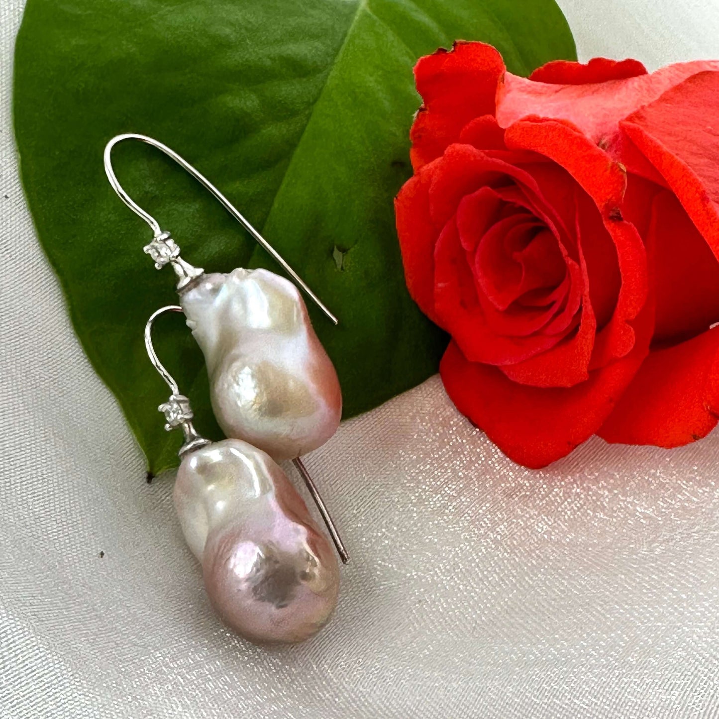 Lavender Baroque Pearl Earrings – close-up against white pearl shell and red rose