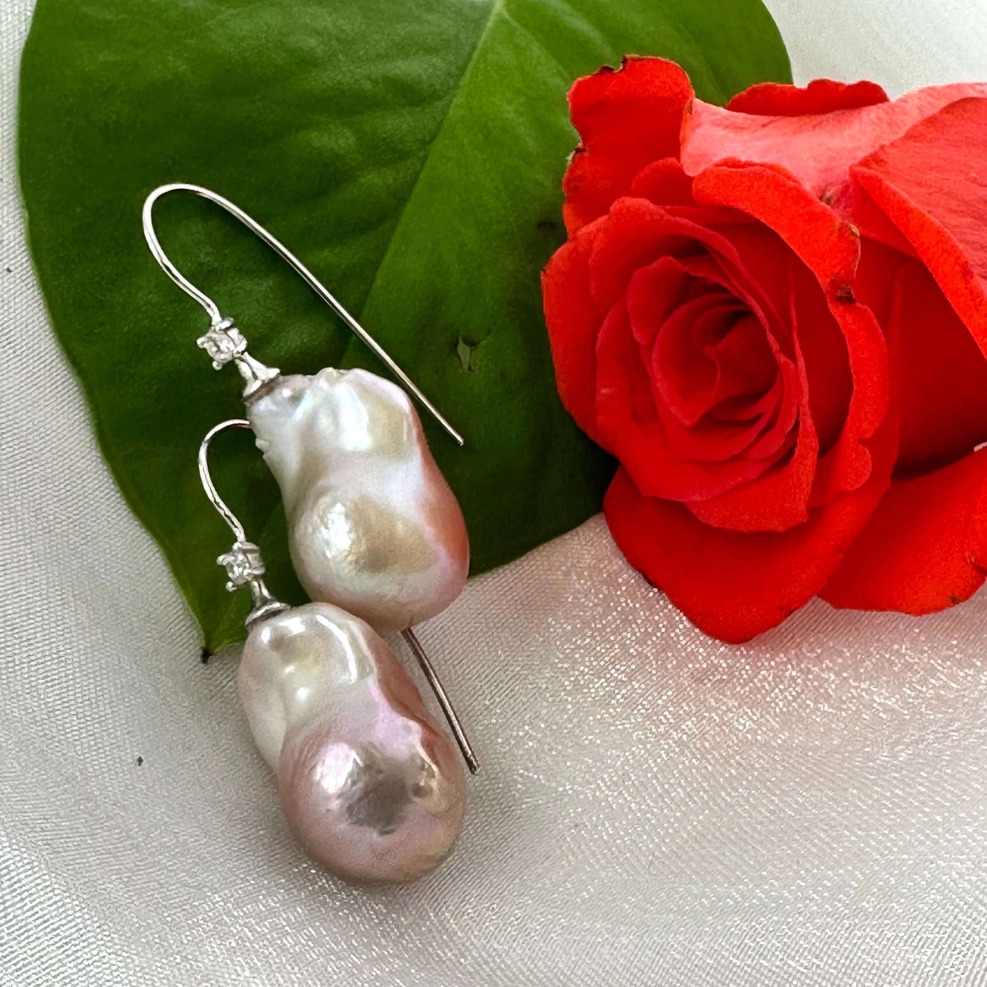 Lavender Baroque Pearl Earrings – close-up against white pearl shell and red rose