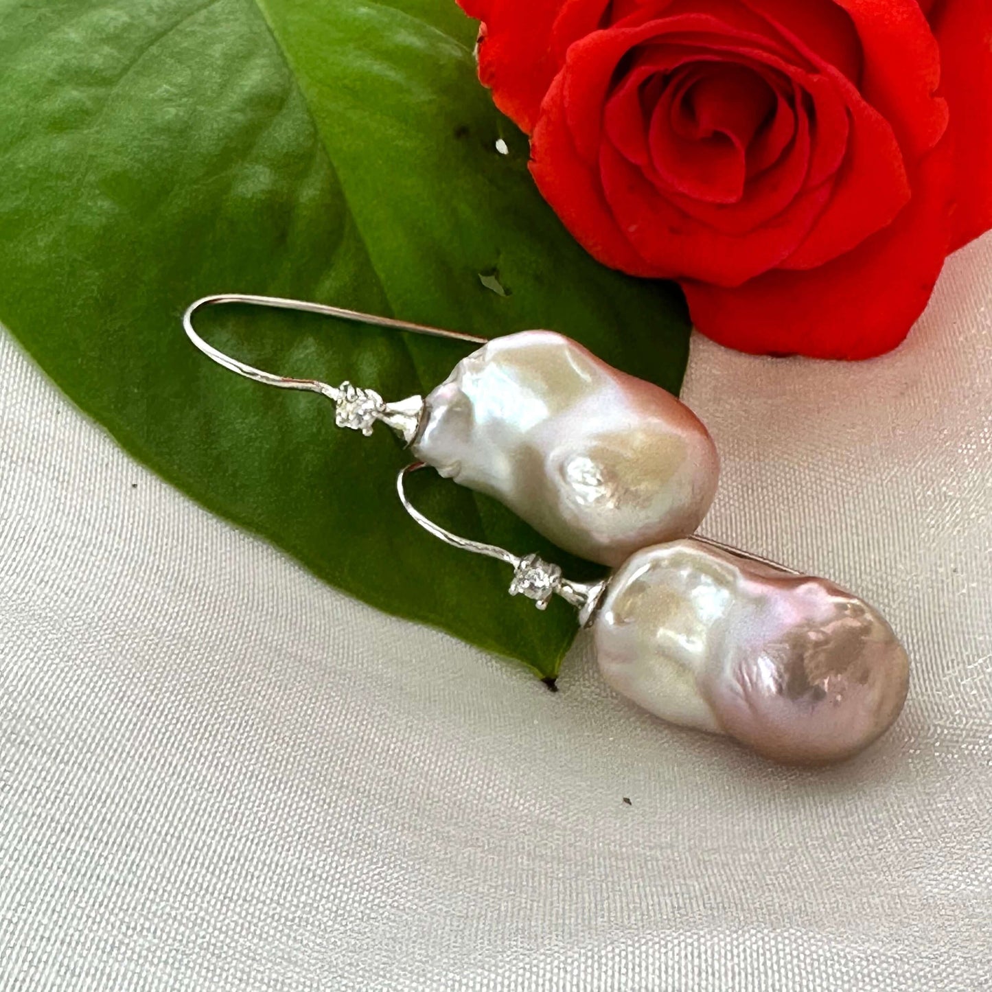 Lavender Baroque Pearl Earrings – close-up against white pearl shell and red rose