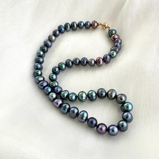 Peacock pearl necklace displayed on white cloth background