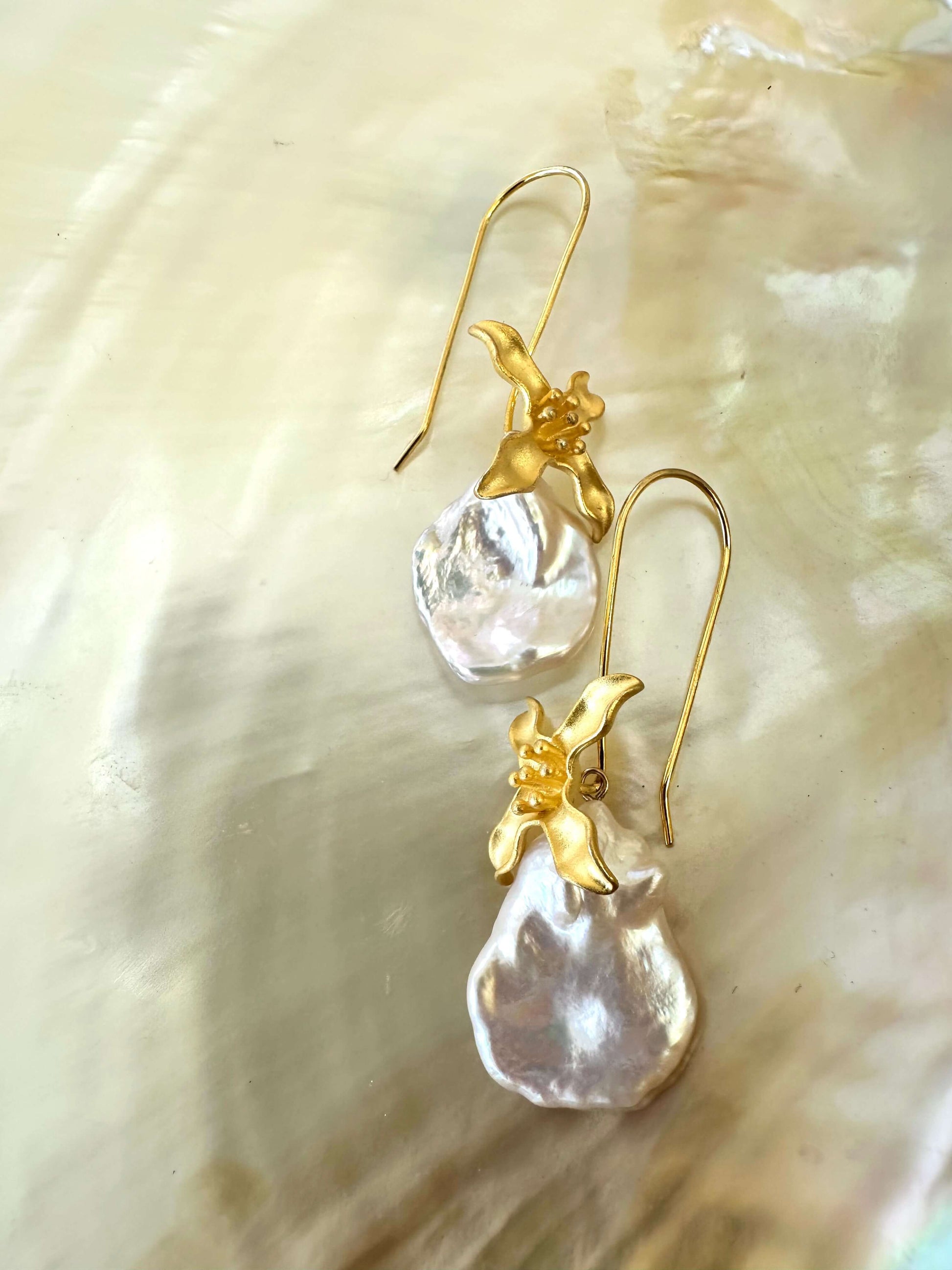 Close-up of Keshi Pearl Earrings with white petal pearls displayed on white pearl shell background.