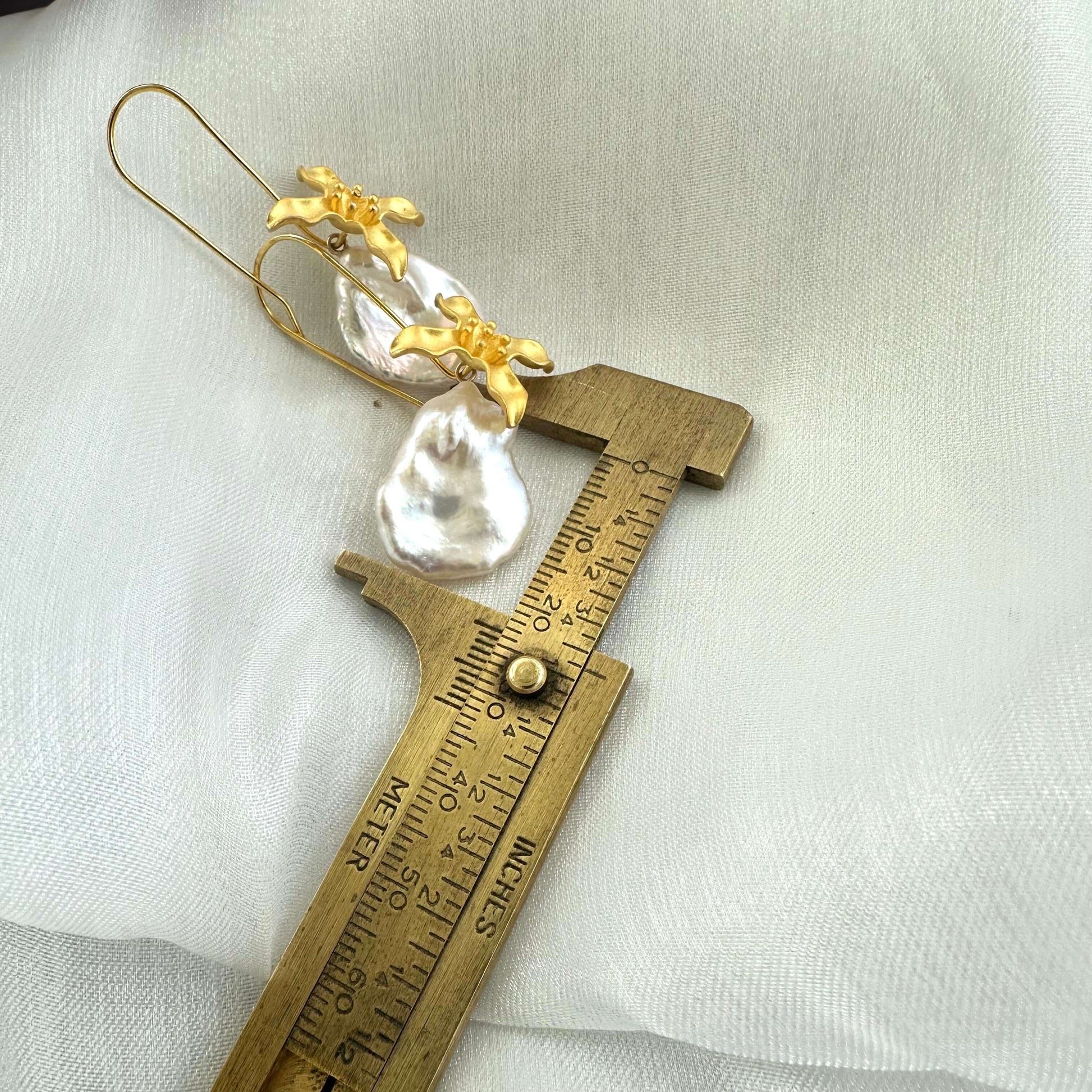 Size reference showing white Keshi pearl from gold vermeil flower earring measured against ruler on white background.