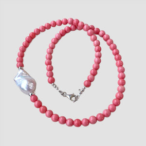Pink coral and one large baroque pearl on the side of the necklace with sterling silver details, measuring 18.5 inches. This vibrant summer jewelry piece is perfect for beach outings and makes a thoughtful gift for her.