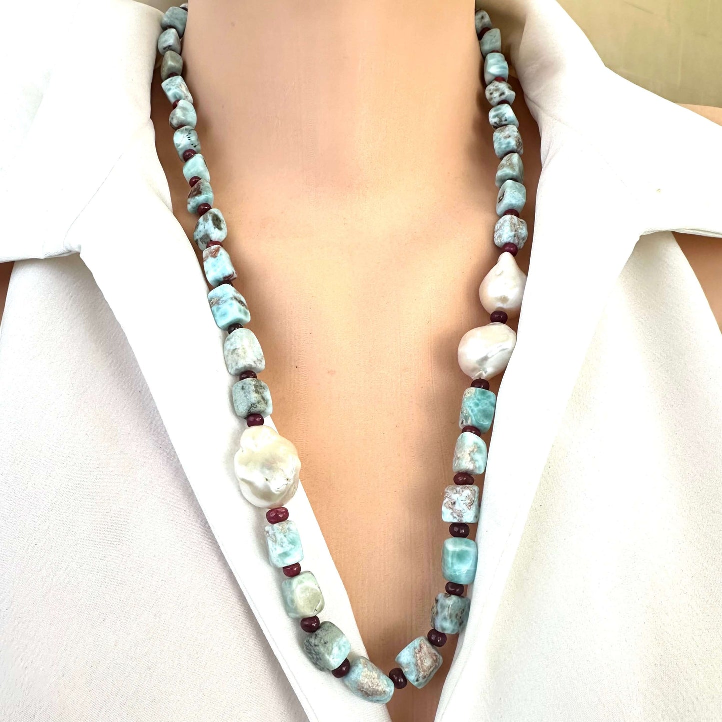 Detailed front view of larimar ruby and baroque pearl necklace showing blue and red gemstones