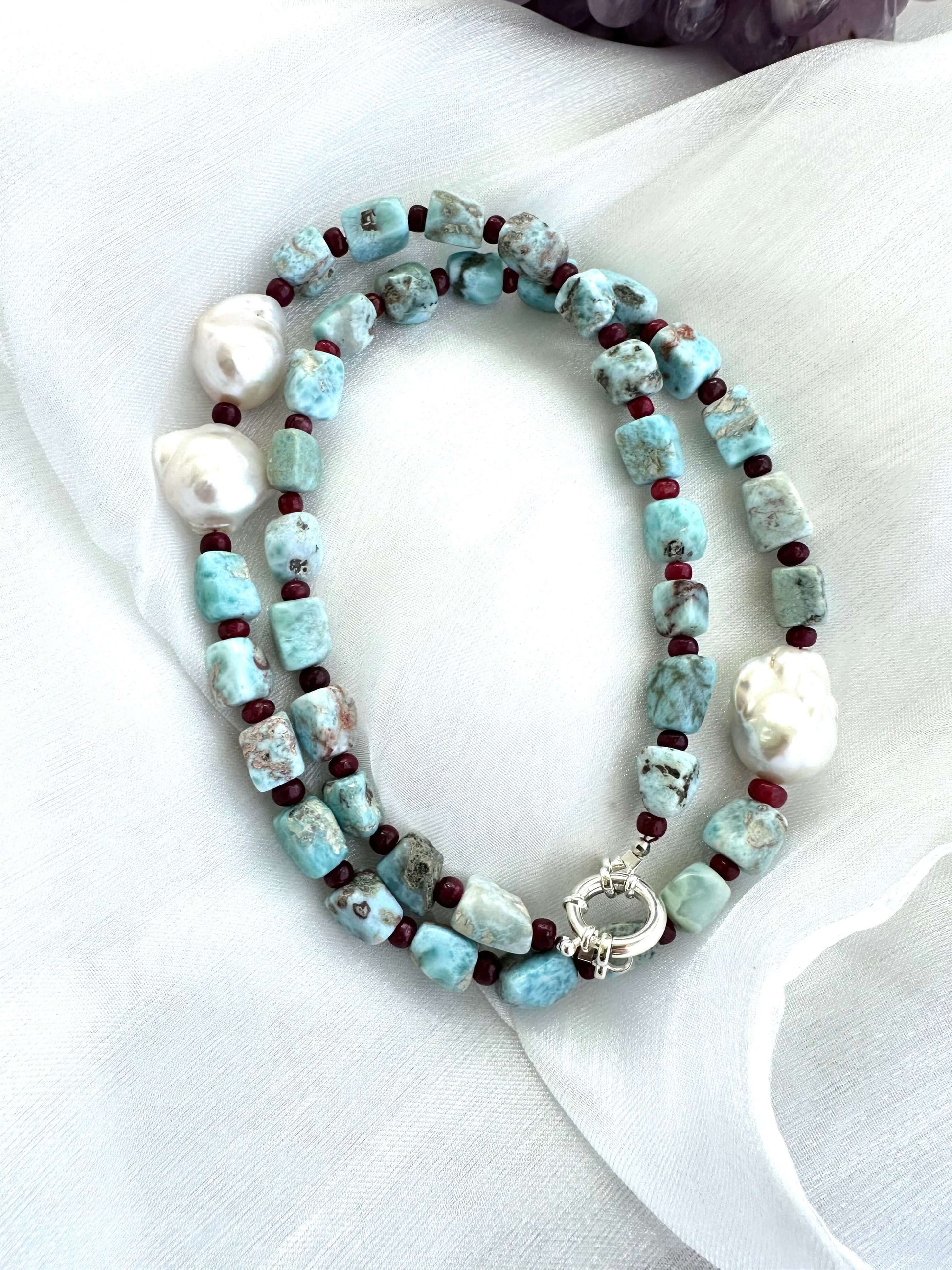Larimar ruby and baroque pearl necklace laid on white background, handcrafted gemstone jewelry