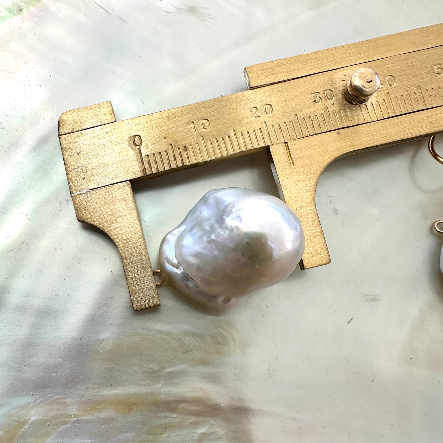 Baroque pearl drops measured against ruler without gold flower studs
