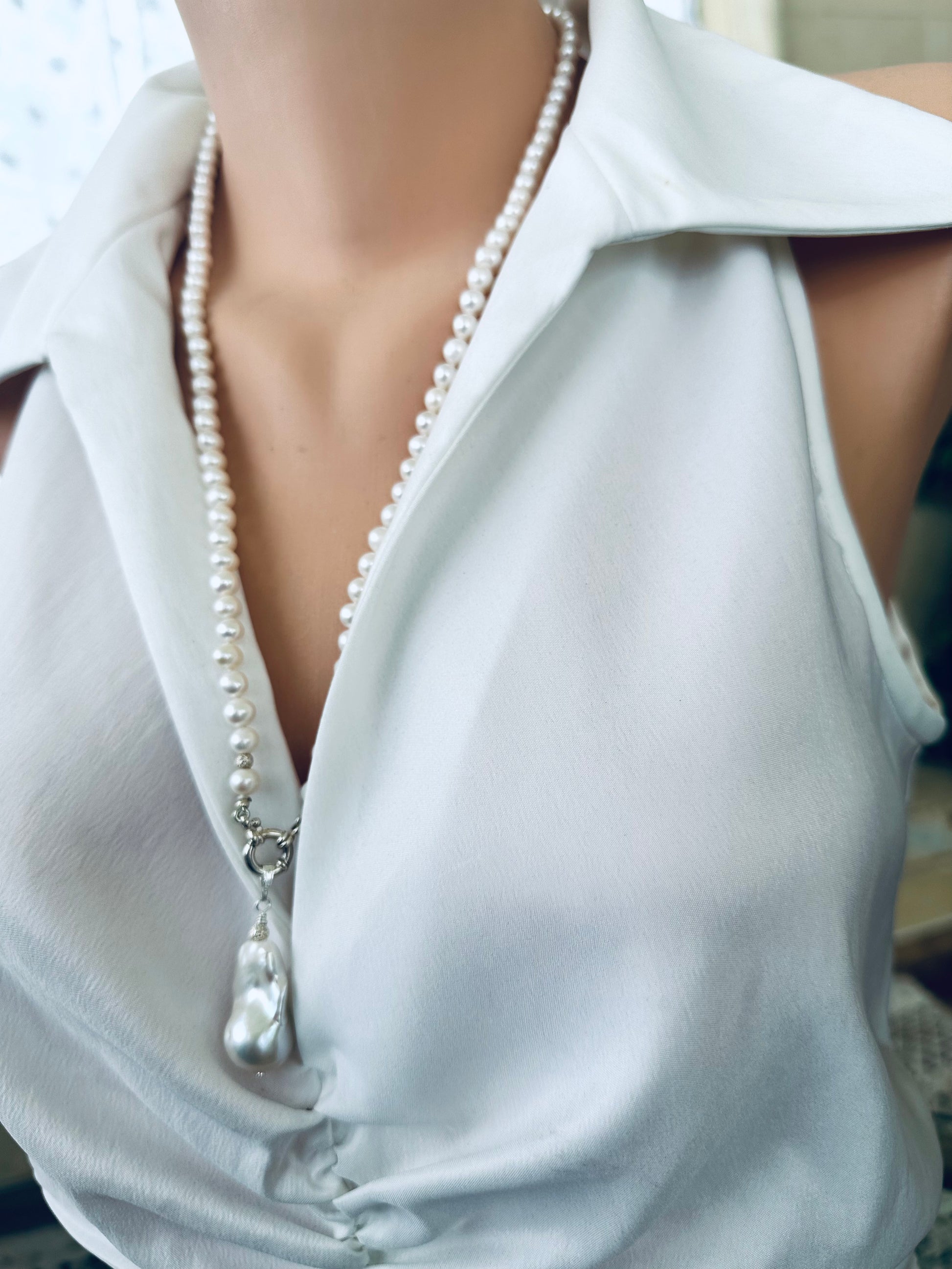 Side view of white pearl necklace with baroque pendant on mannequin display