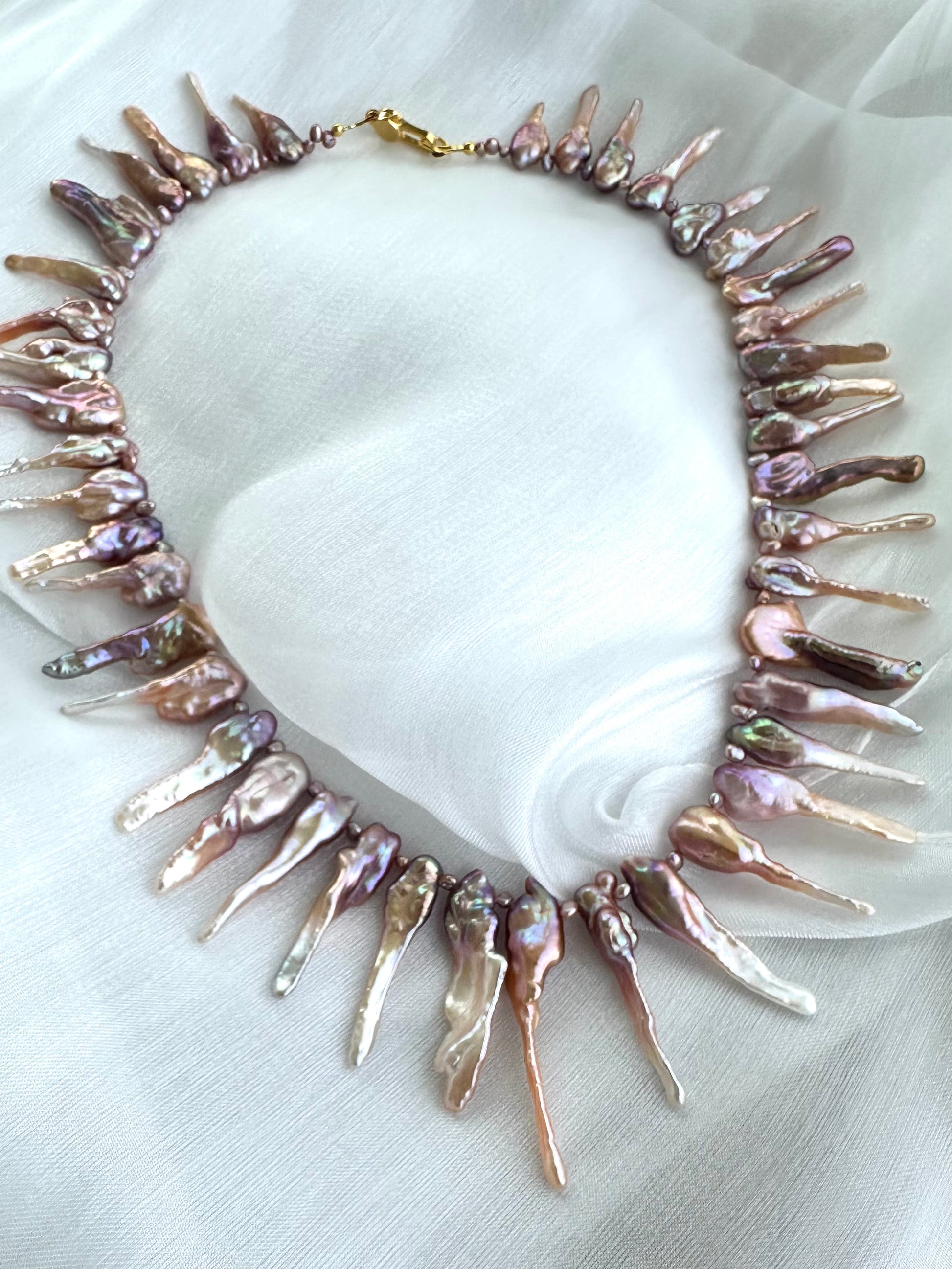 Close-up of pink Biwa pearl necklace showing purplish-pink luster on fabric