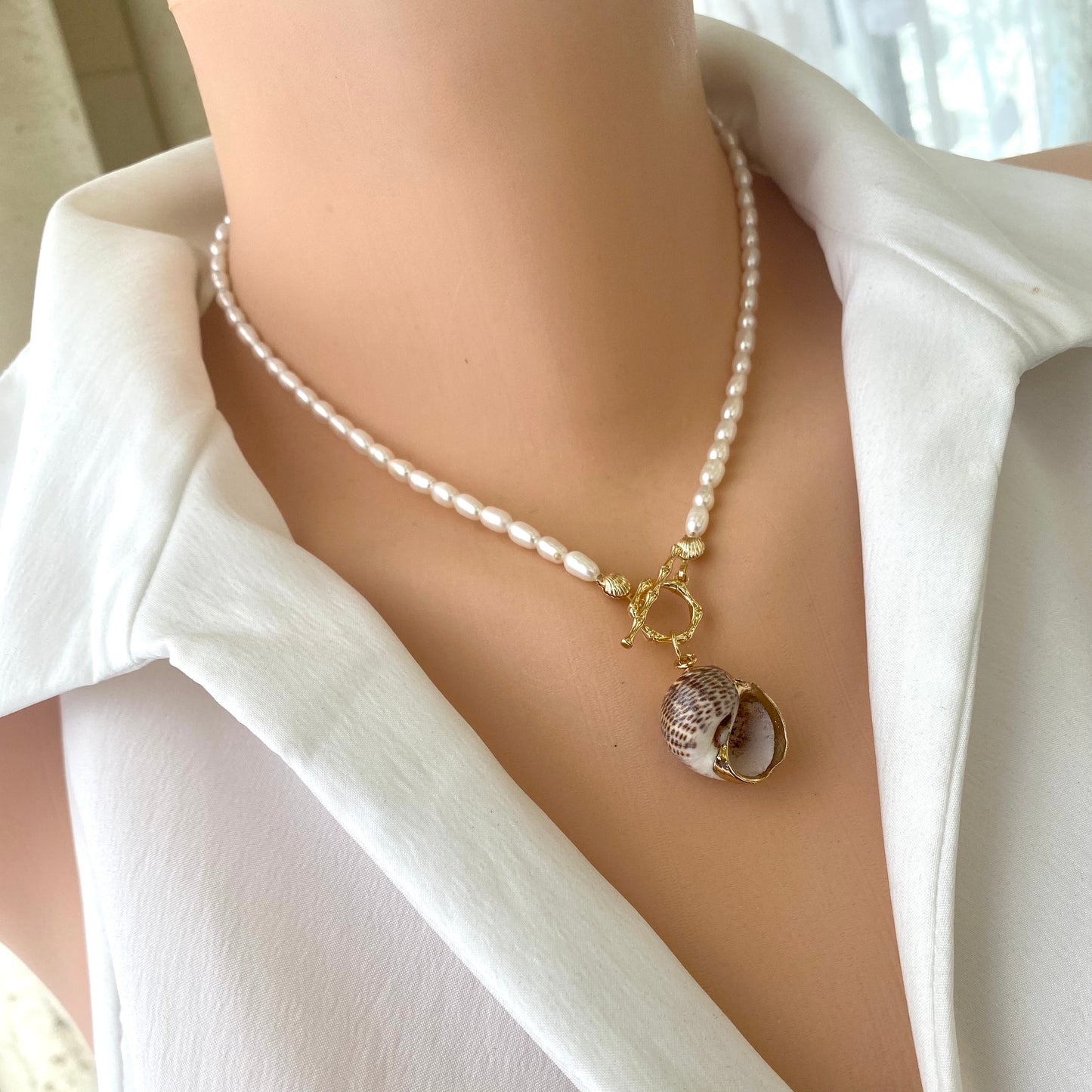 Real seashell pendant pearl necklace worn on model featuring freshwater pearls and gold toggle clasp