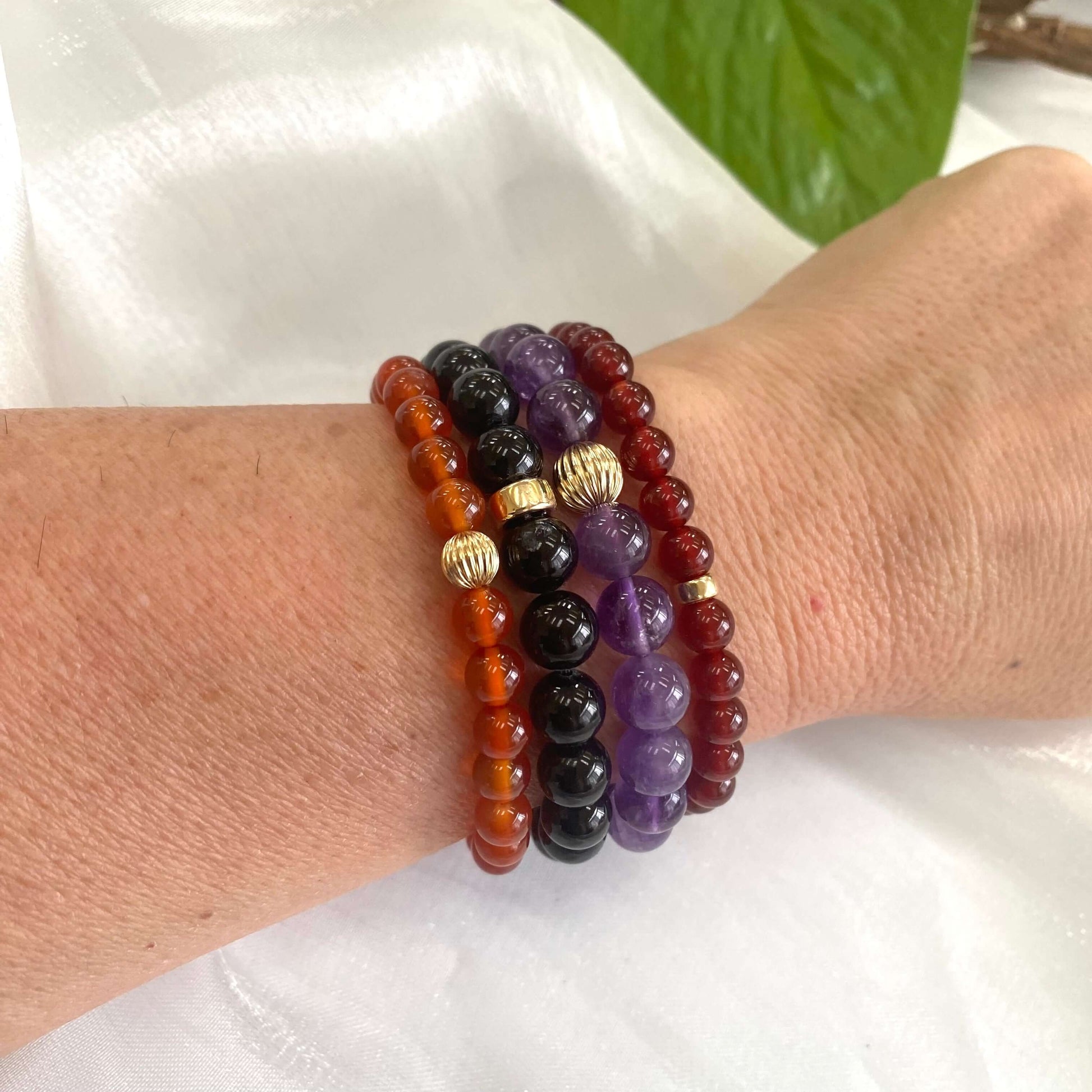 Amethyst bracelet worn on wrist with multiple stacked gemstone bracelets