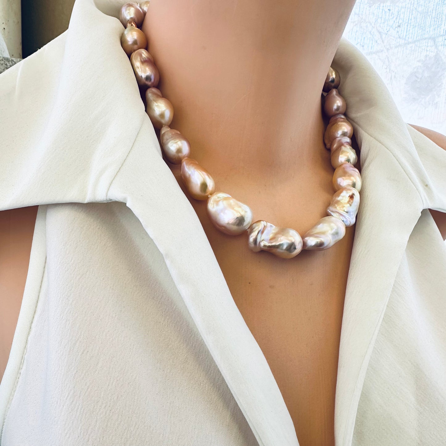Side angle of golden pink baroque pearl necklace on mannequin, lustrous pearls