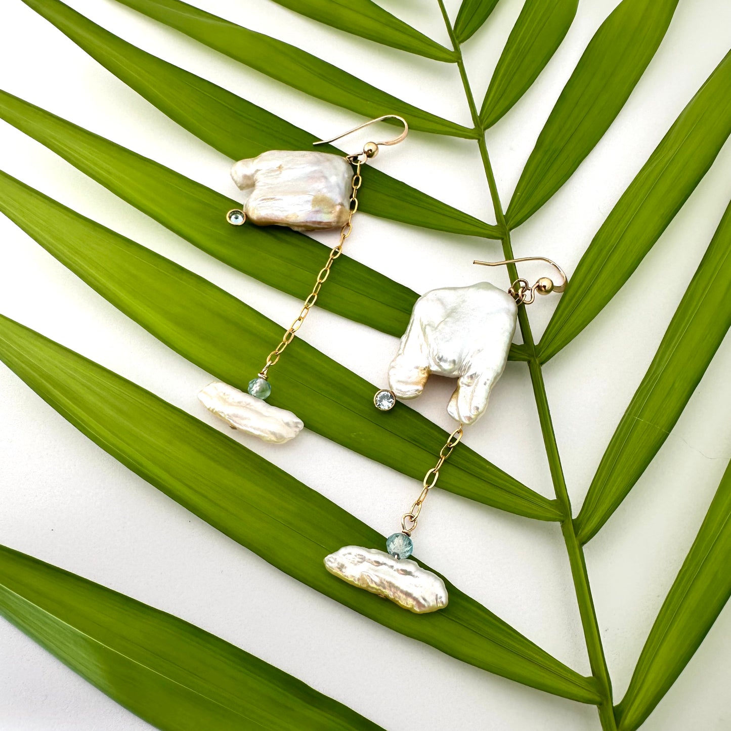 Boho pearl earrings gold filled held against leafy green background — handcrafted square pearl earrings with blue accent by Loulia Pearl Jewelry