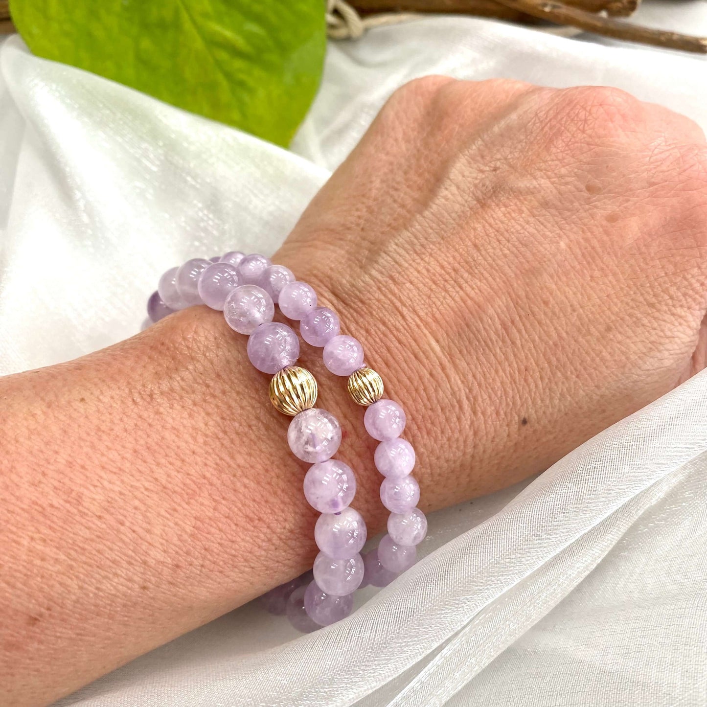 lavender amethyst stretch bracelet worn on wrist with gold accents and soft purple beads.