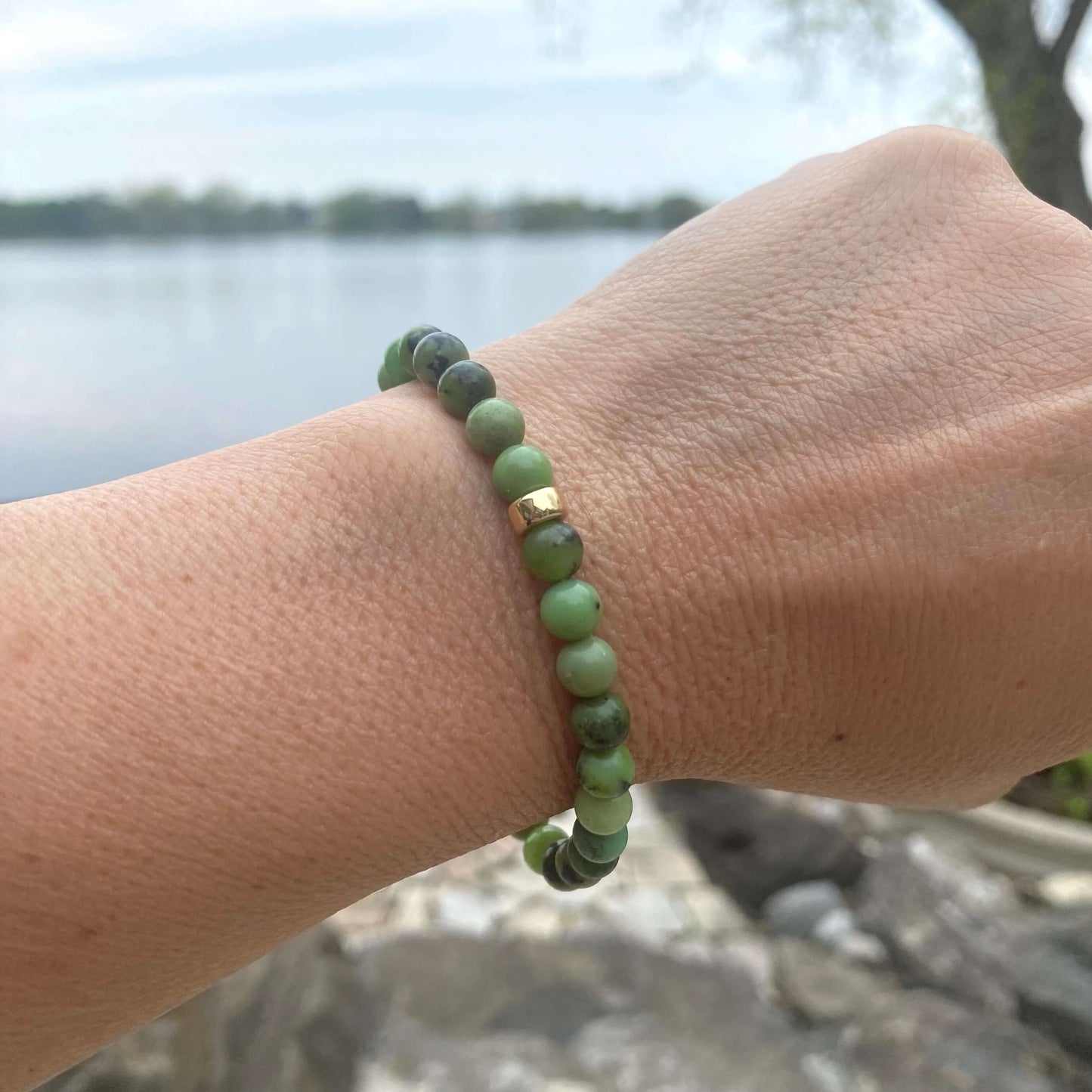 Chrysoprase stretch bracelet with 6mm beads and 14K gold filled accents worn outdoors by a lake.