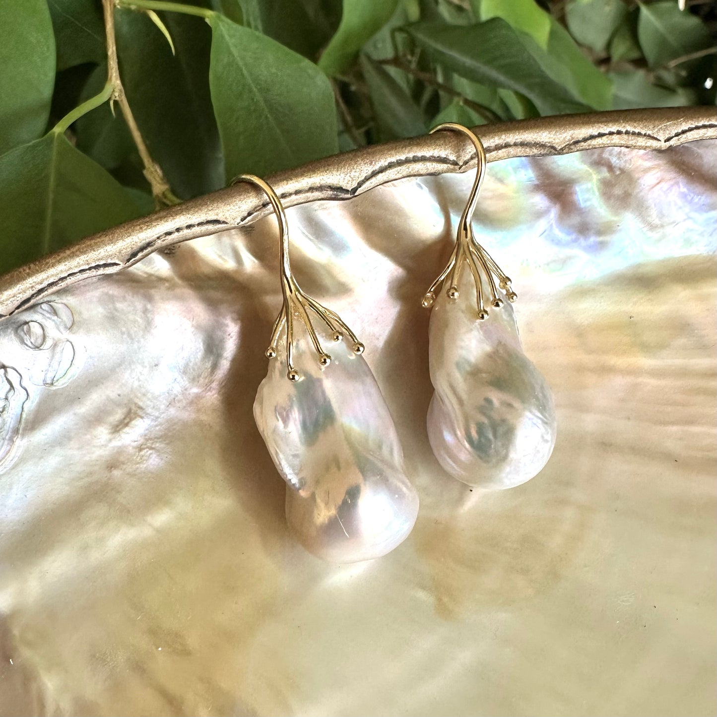 Close-up of freshwater baroque pearl earrings showing iridescent pink green hues on pearl shell surface