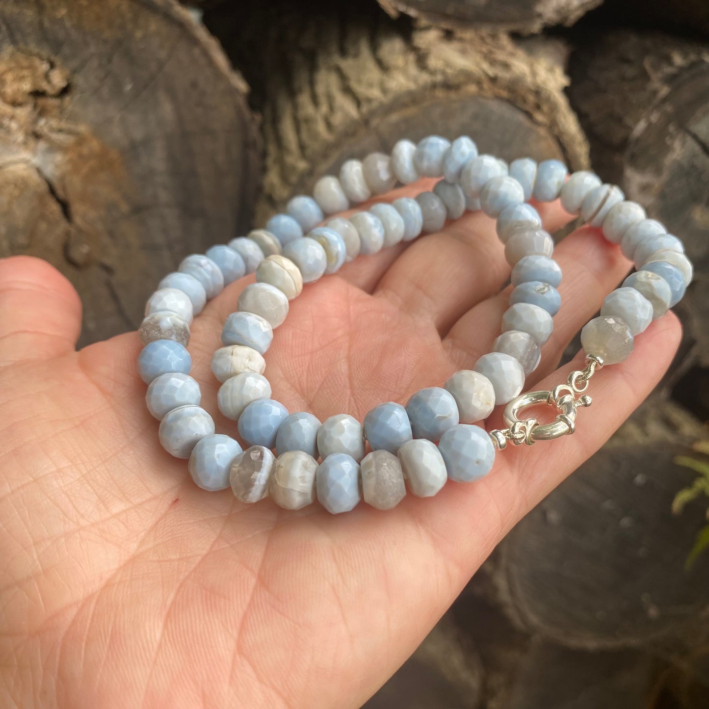 Close-up of blue grey opal necklace showing faceted opal beads against wooden background