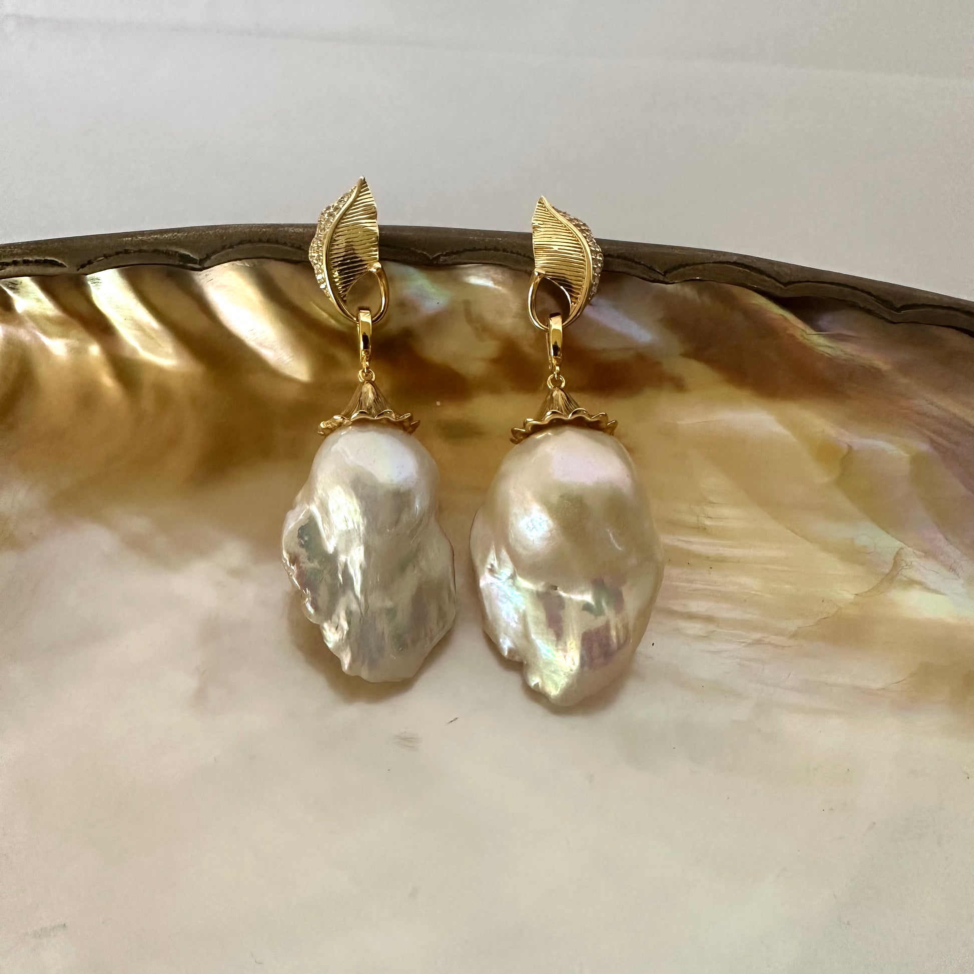 Leaf Design Pearl Earrings with gold vermeil accents and baroque pearl drops on a decorative plate.