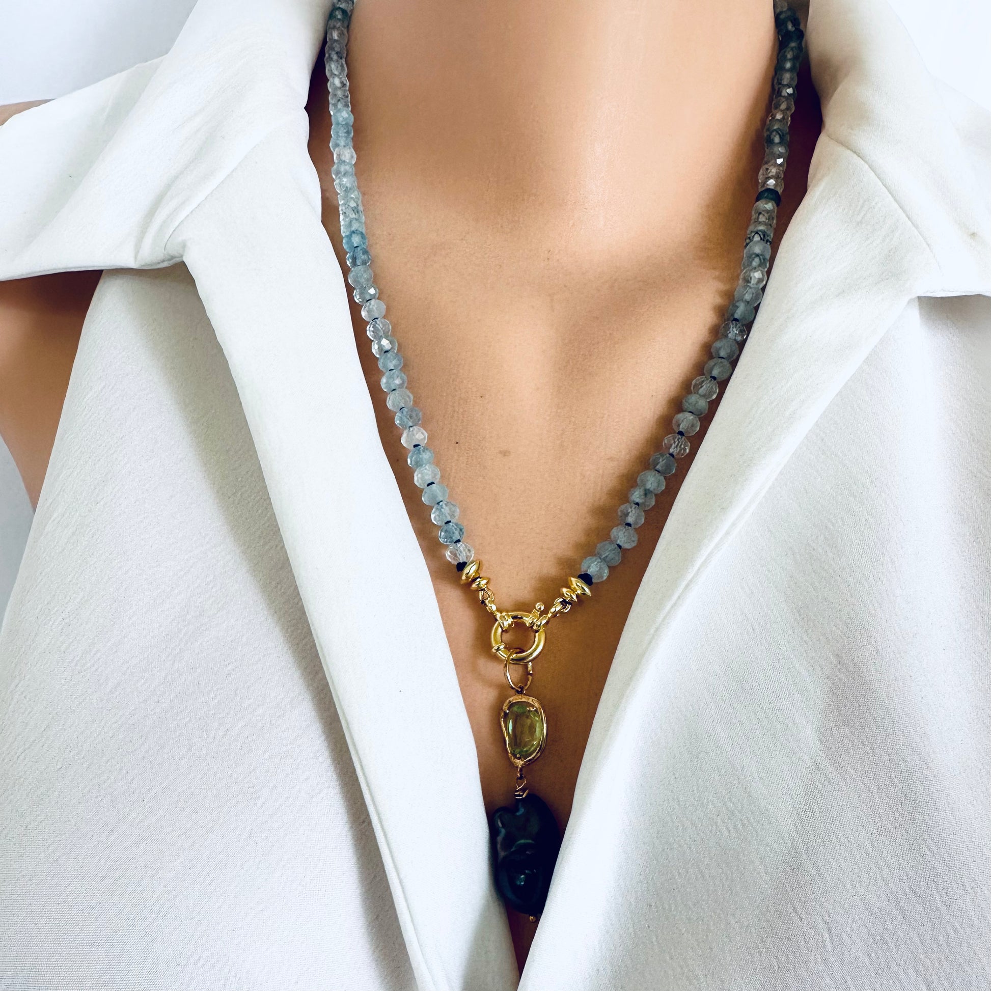 Aquamarine baroque pearl necklace featuring soft blue beads and a gold pendant, worn on a mannequin.