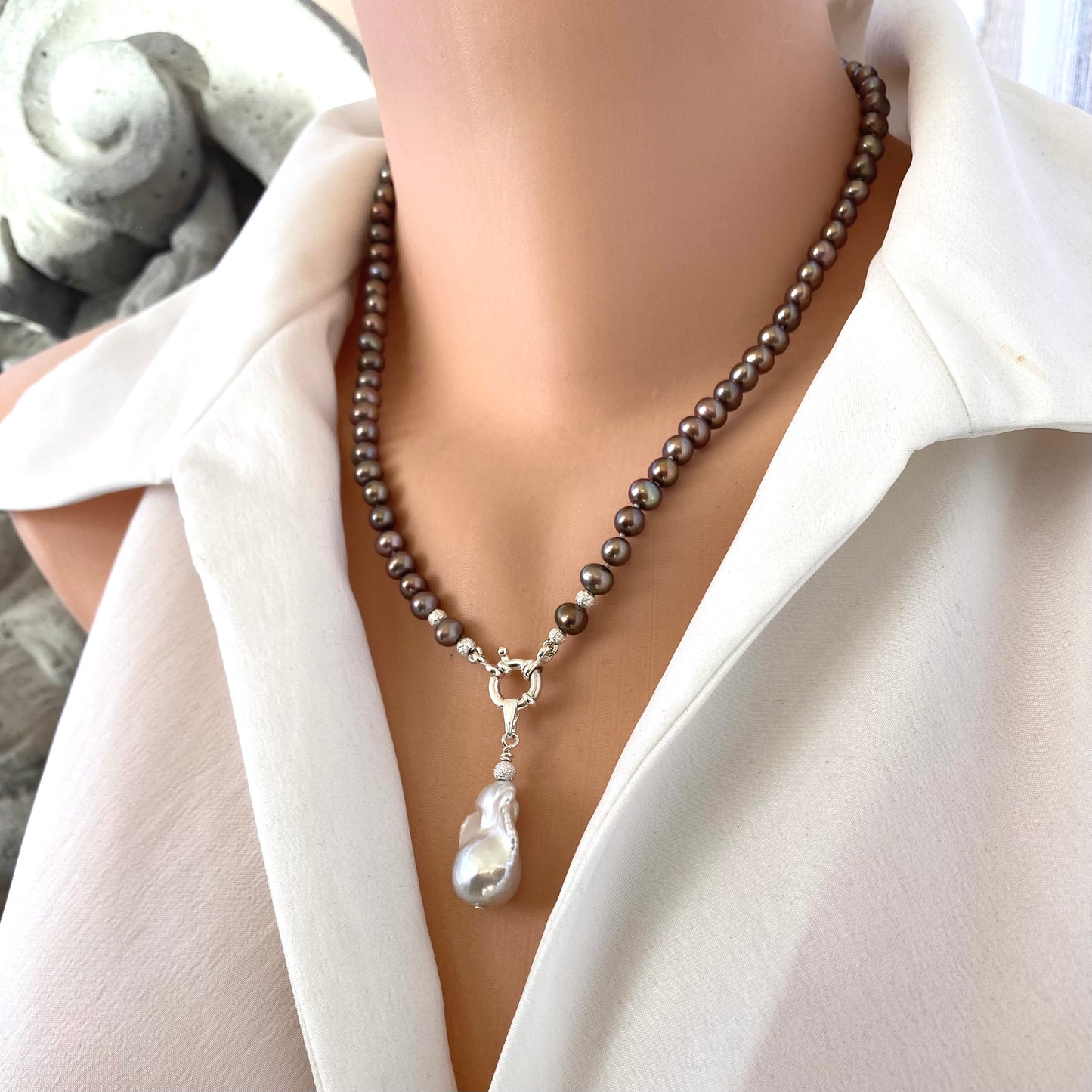 Bronze pearl necklace with white baroque pendant worn on mannequin, showing soft bronze hues and sterling silver clasp detail.