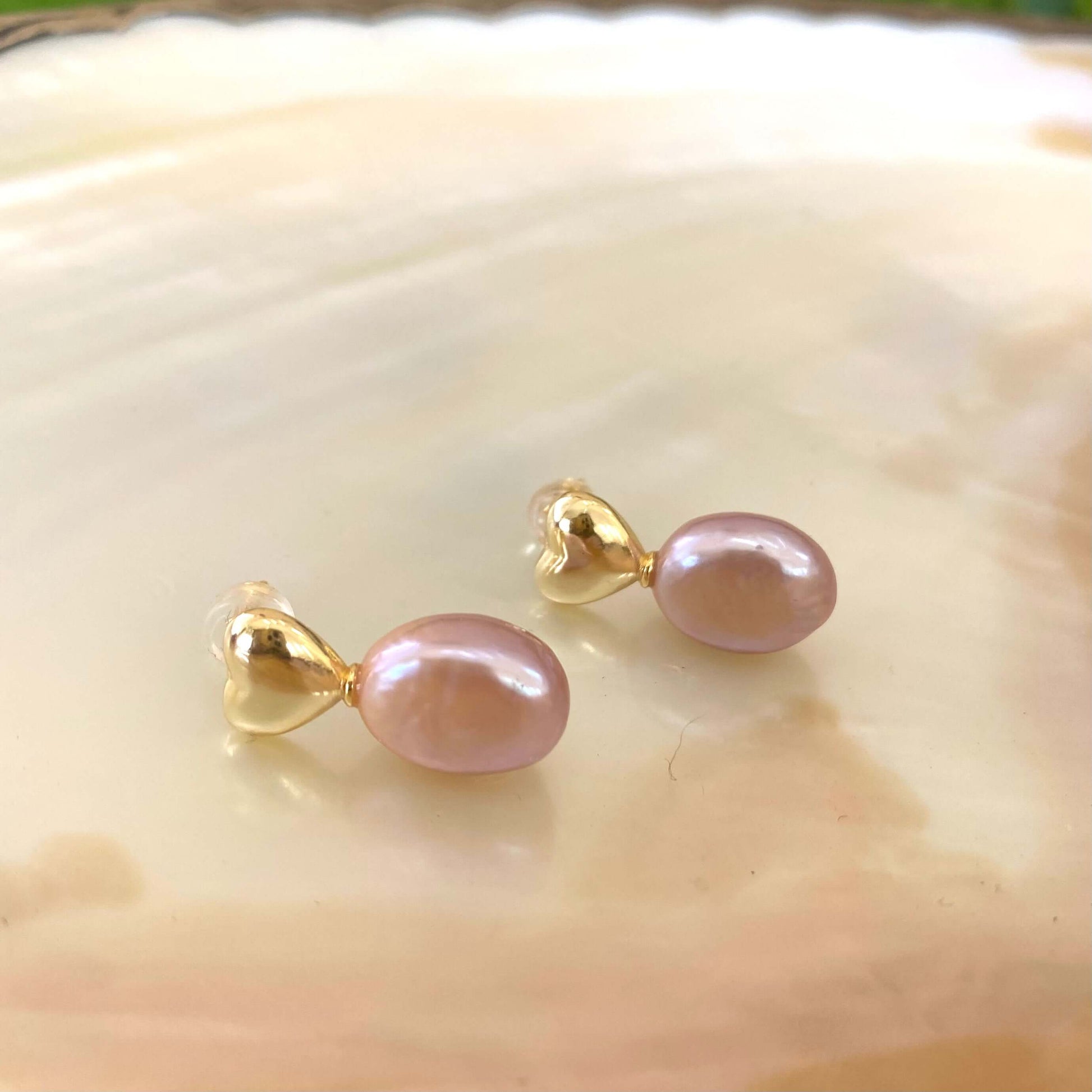 Heart Pearl Earrings – gold version close-up against white pearl shell