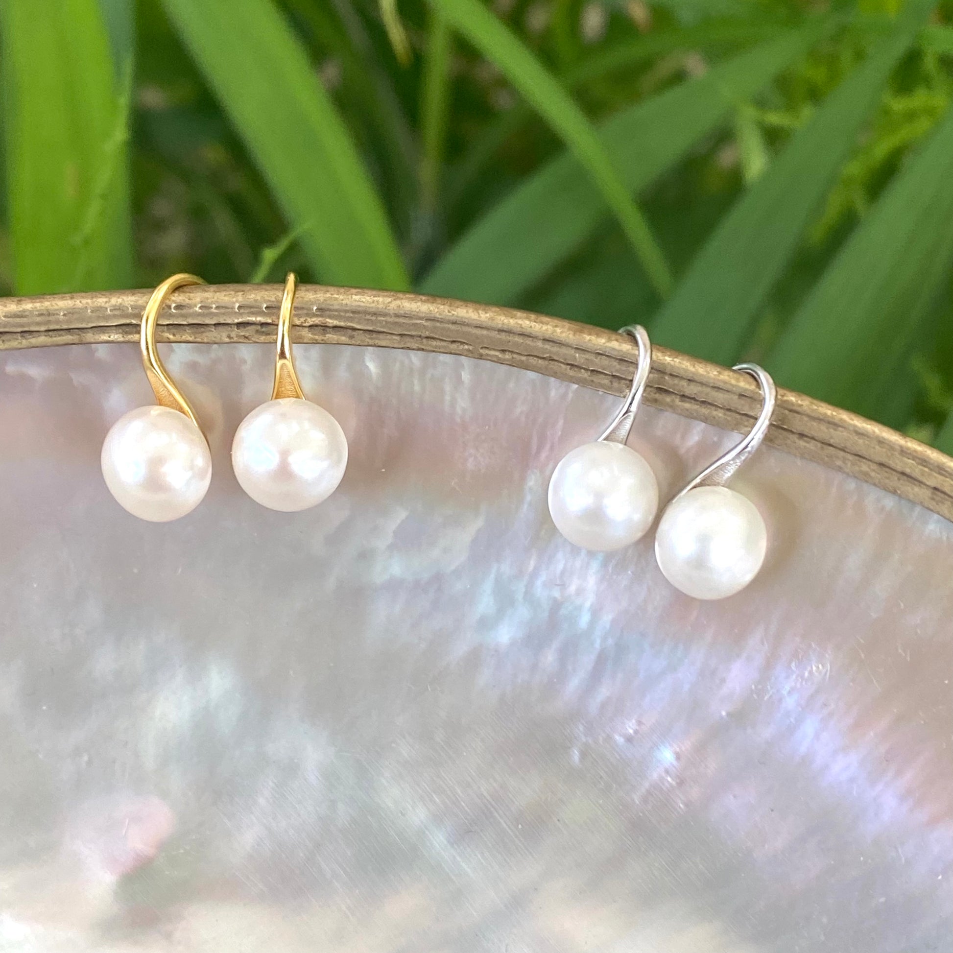 Button Pearl Earrings – gold and silver sets dangling from pearl shell and green leaves