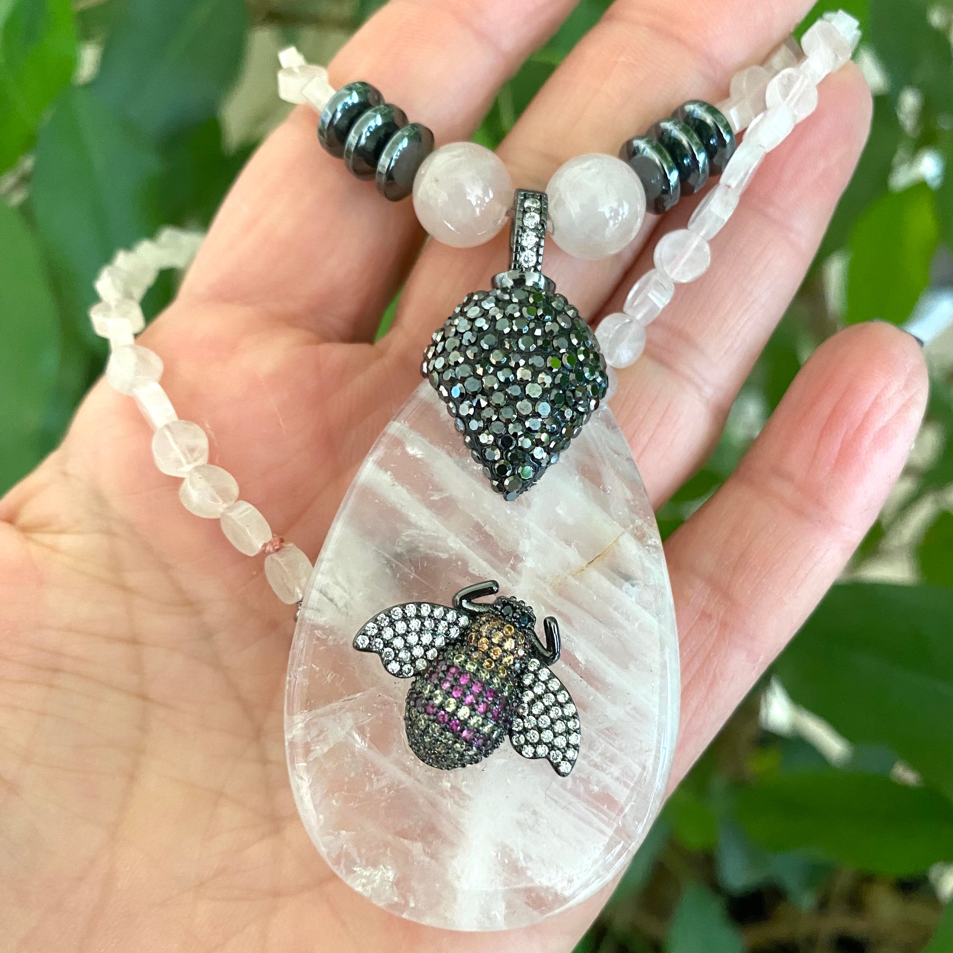 Rose quartz necklace with rhinestone pavé bee pendant showcasing elegant design and soft blush tones.