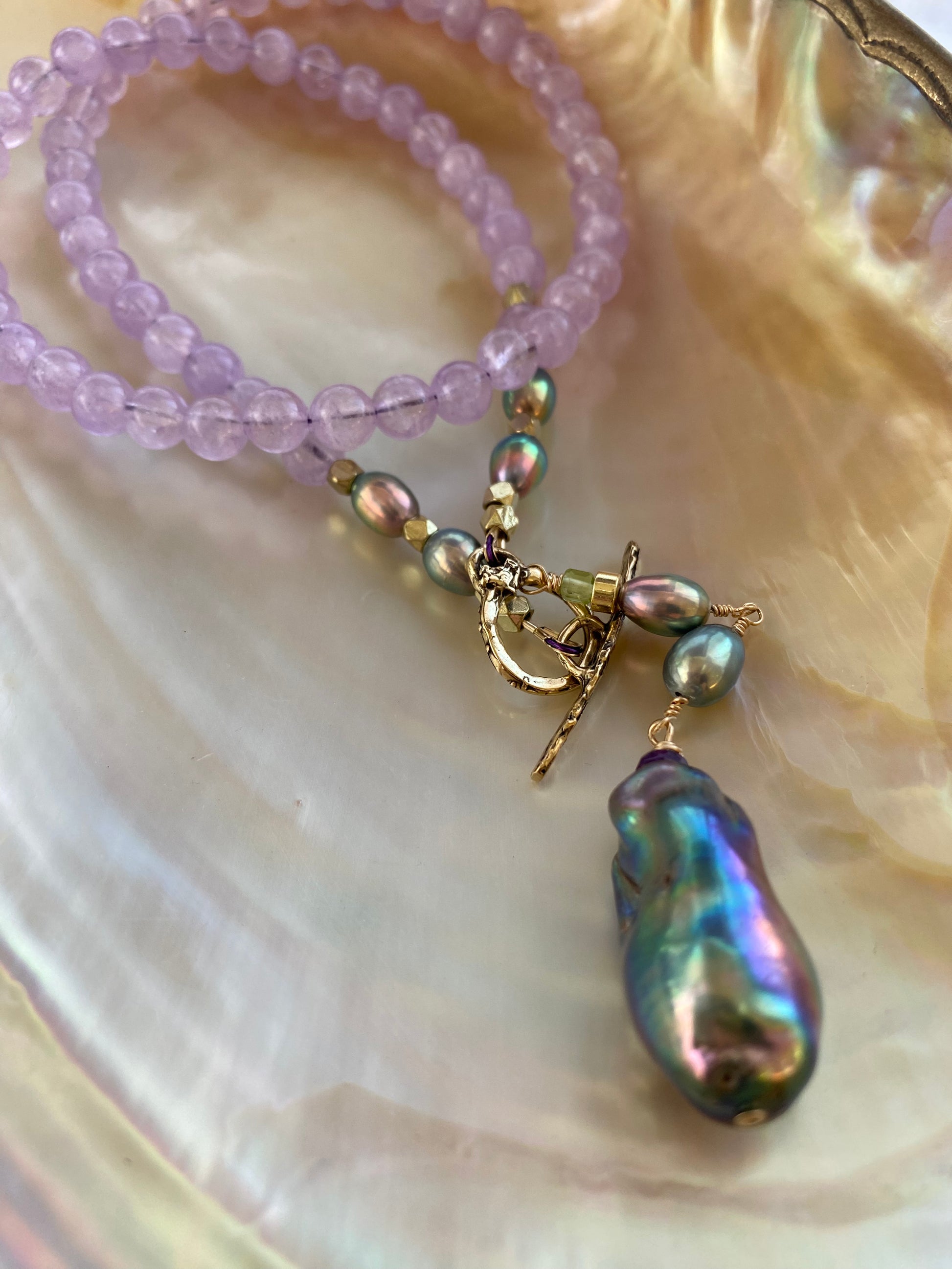 Amethyst Pearl Necklace with gold toggle clasp and baroque pearl pendant on white pearl shell backdrop.
