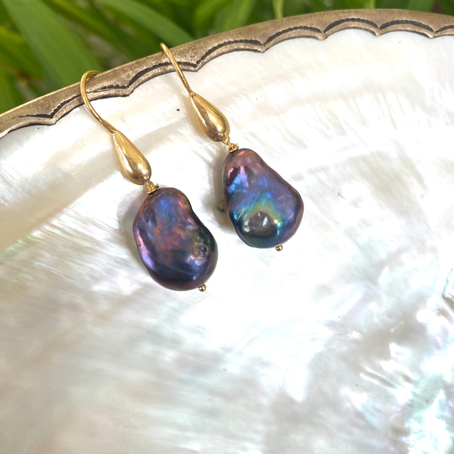 Close-up of baroque pearl drop earrings highlighting peacock tones and gold vermeil details