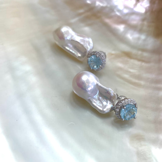 Blue topaz pearl drop earrings displayed on white pearl shell background