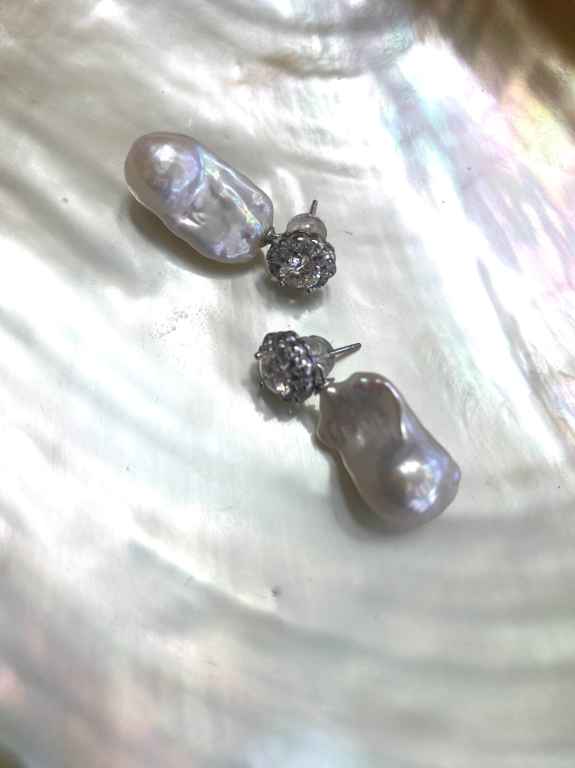 Elegant moissanite and baroque pearl earrings close-up, diamond-like sparkle and organic pearls.