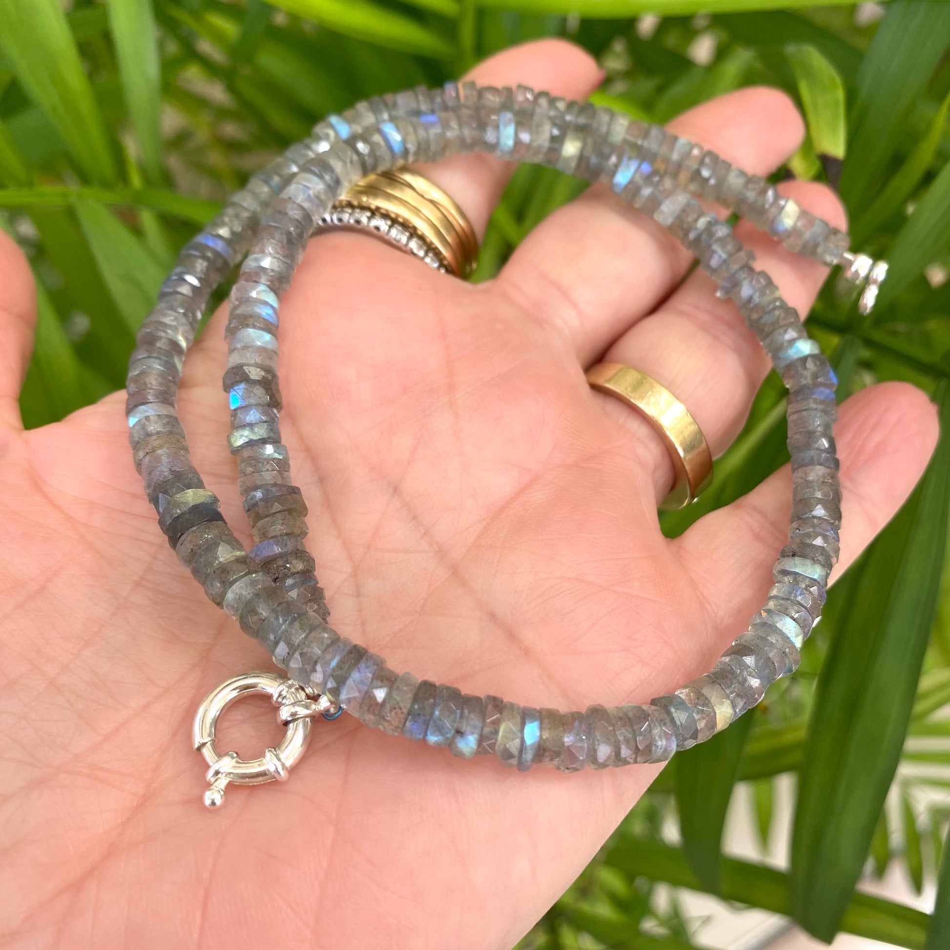 Labradorite aquamarine pendant necklace without pendant held in hand against leafy green background — handcrafted gemstone jewelry by Loulia Pearl Jewelry